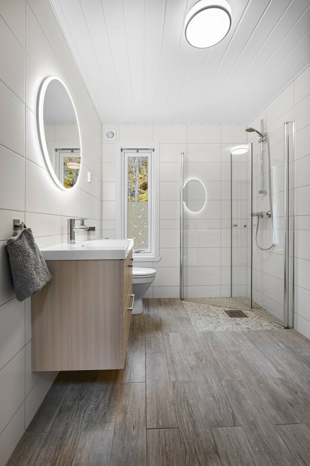 Badet er helfliset og pent. Dette måler 5,1 kvm og er utstyrt med toalett, dusj og baderomsmøbelement med nedfeldt vask i porselen. Badet er romslig og fremstår som "nytt". Galleribilde