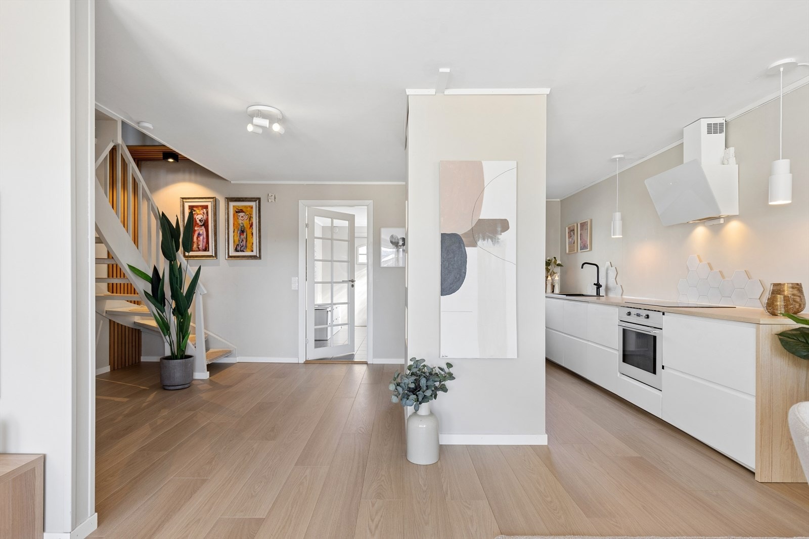 Fra stuen leder en malt tretrapp med teppefliser i trinnene opp til boligens andre etasje. Galleribilde