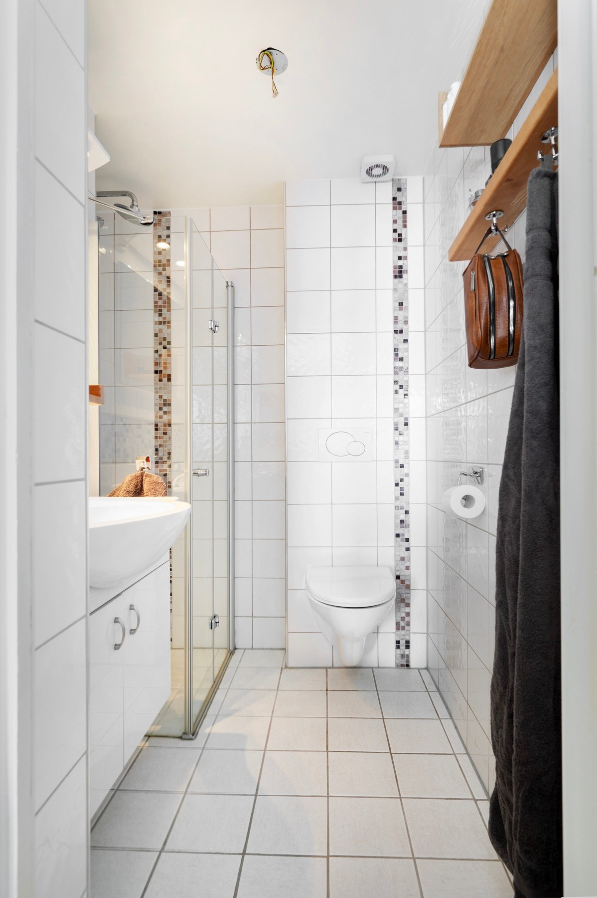 Badet mot øst har fliser på vegger og gulv med gulvvarme. Innredet med vegghengt toalett, servantinnredning, speil og dusjnisje. Galleribilde
