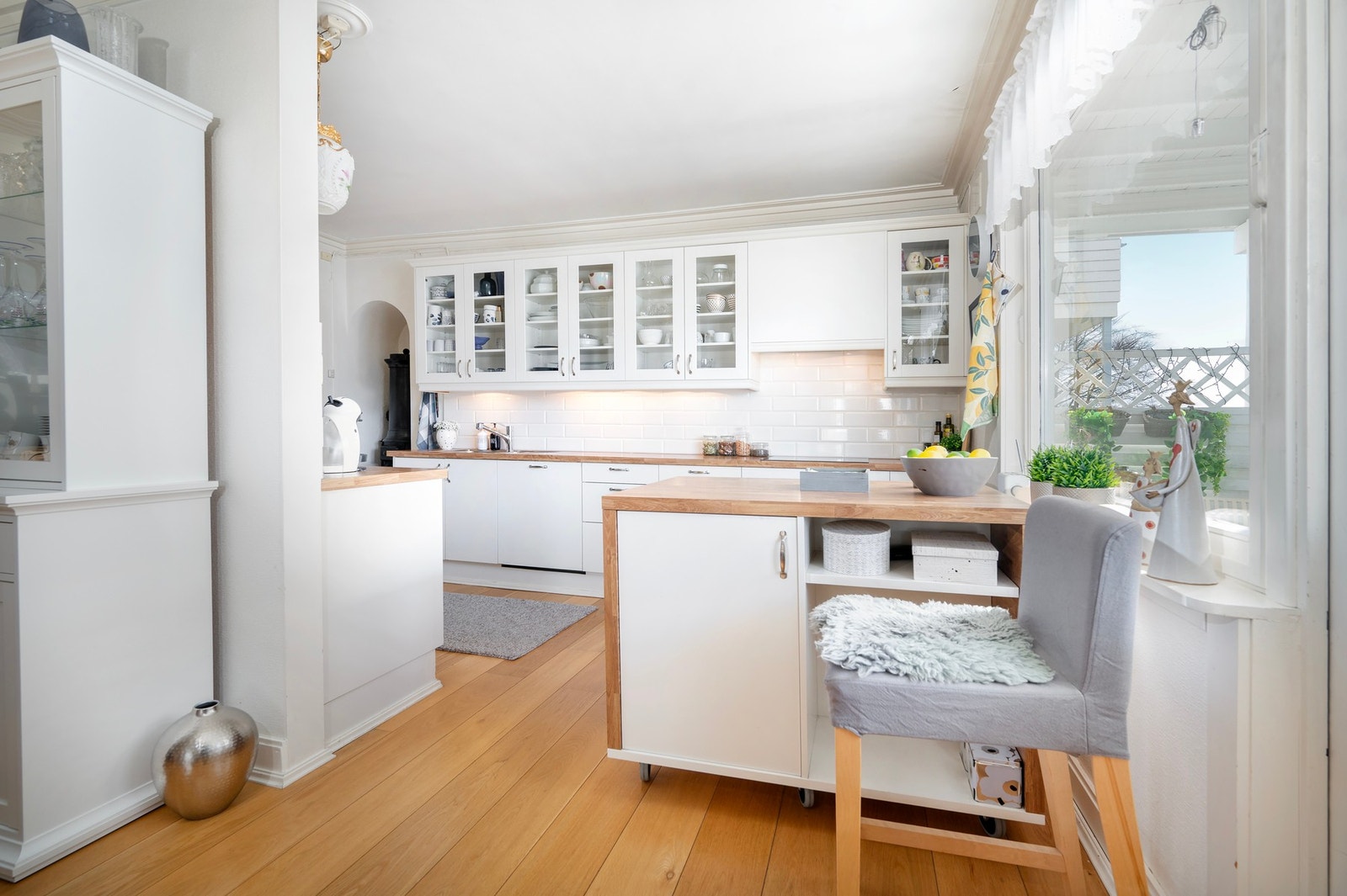 Fin kjøkkeninnredning med hvite glatte fronter og fliser på vegger over laminat benkeplate. Galleribilde
