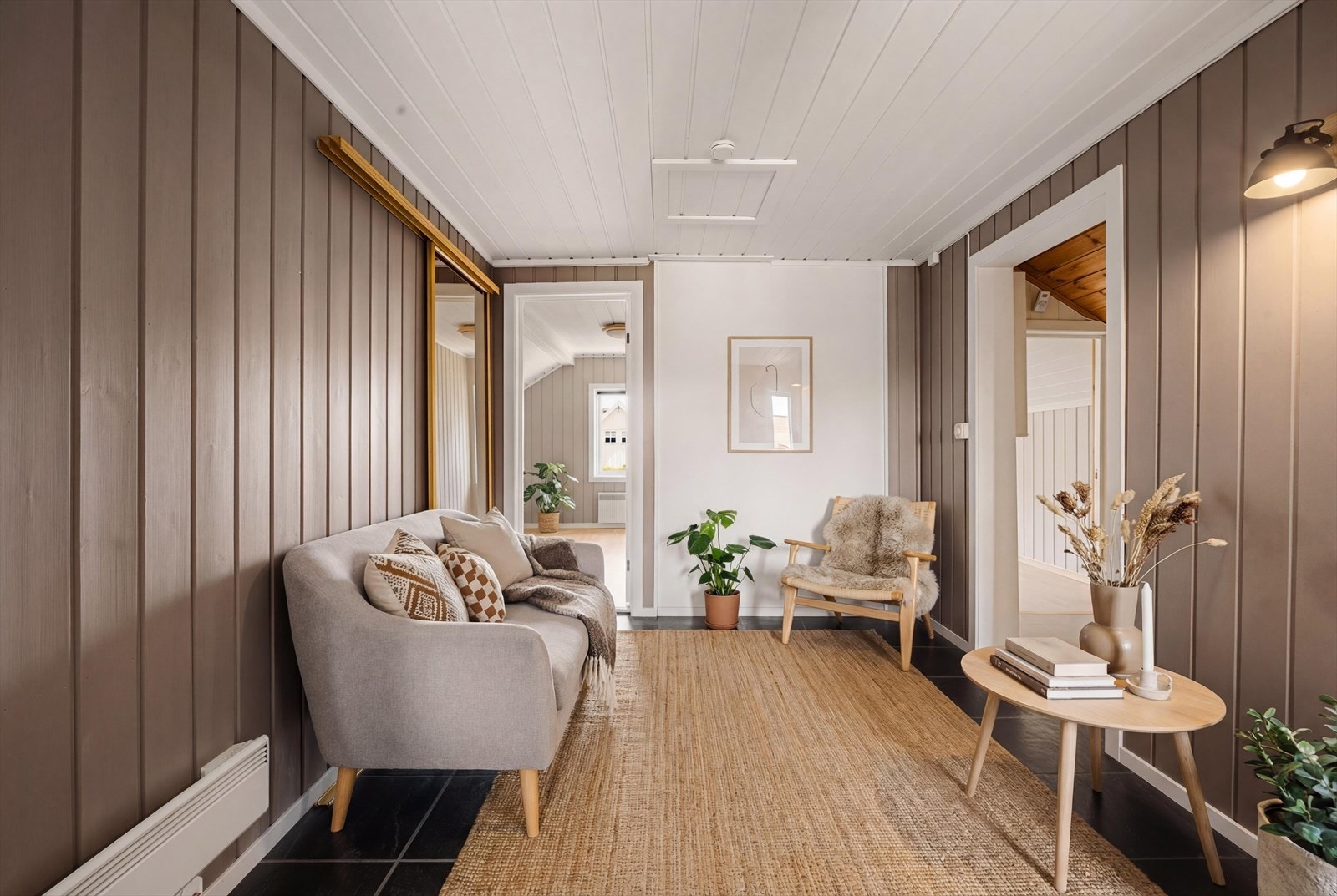Stuen er med flislagte gulv, og panel på vegger. Herfra er det tilkomst til 4 gode soverom, samt en stor garderobe bak sofaen. Rommet er digitalt møblert. foto: Fredrik Hansson. Galleribilde
