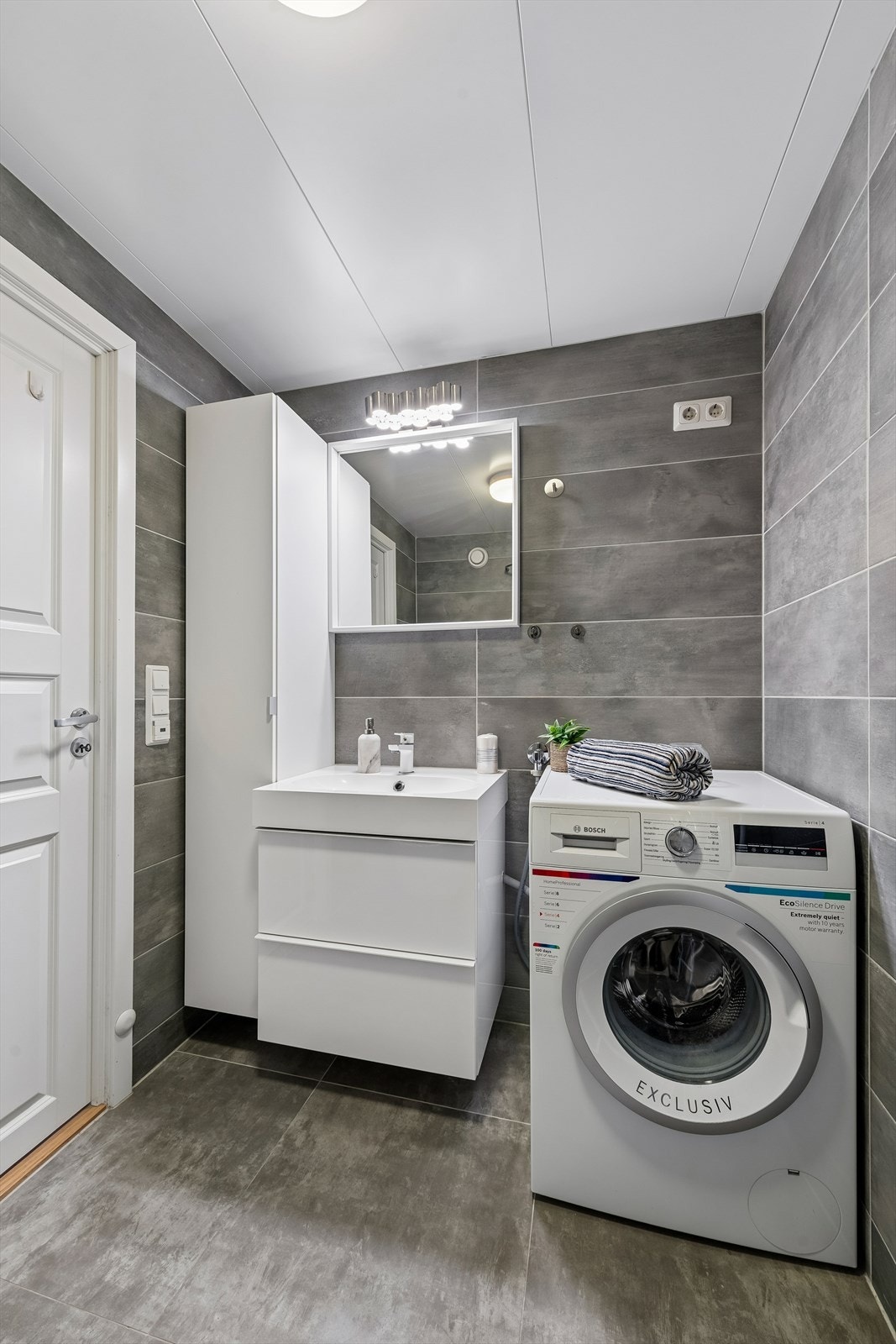Badet har plass til vaskemaskin og oppbevaring. Funksjonelt rom som dekker hverdagens behov. Galleribilde
