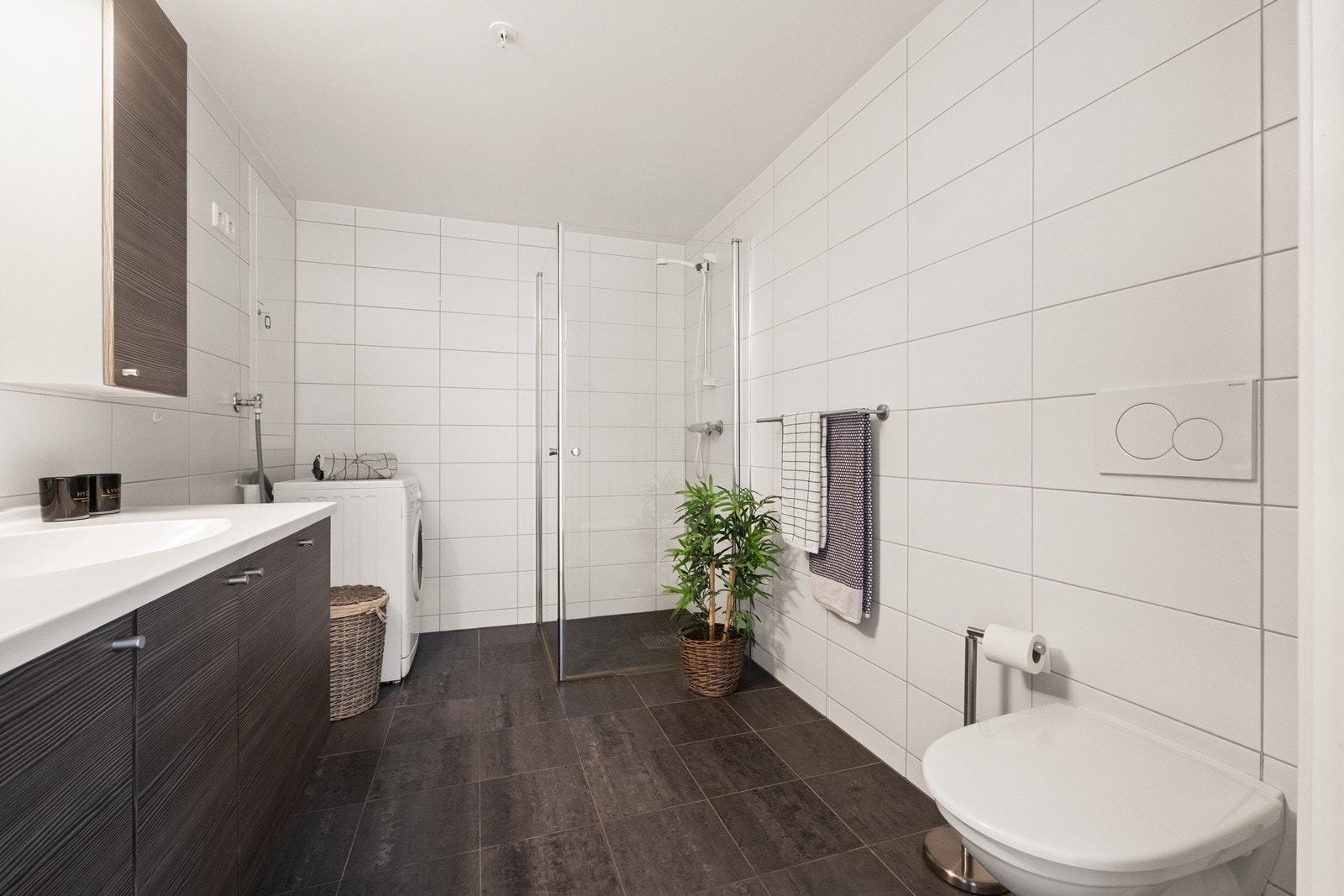 Badet er stort og romslig, og utstyrt med vegghengt wc, baderomsinnredning, dushjørne med glassvegger og opplegg til vaskemaskin. Galleribilde
