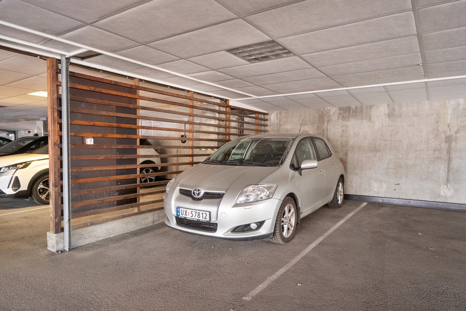 Leiligheten har egen parkeringsplass under tak, like utenfor porten til det lukkede parkeringsarealet. Galleribilde