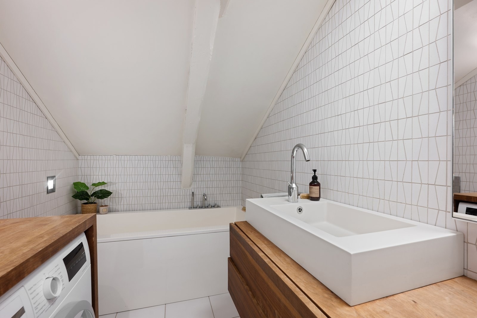 Badet kombinerer funksjonalitet og velvære, med et deilig badekar som inviterer til lange, rolige stunder Galleribilde
