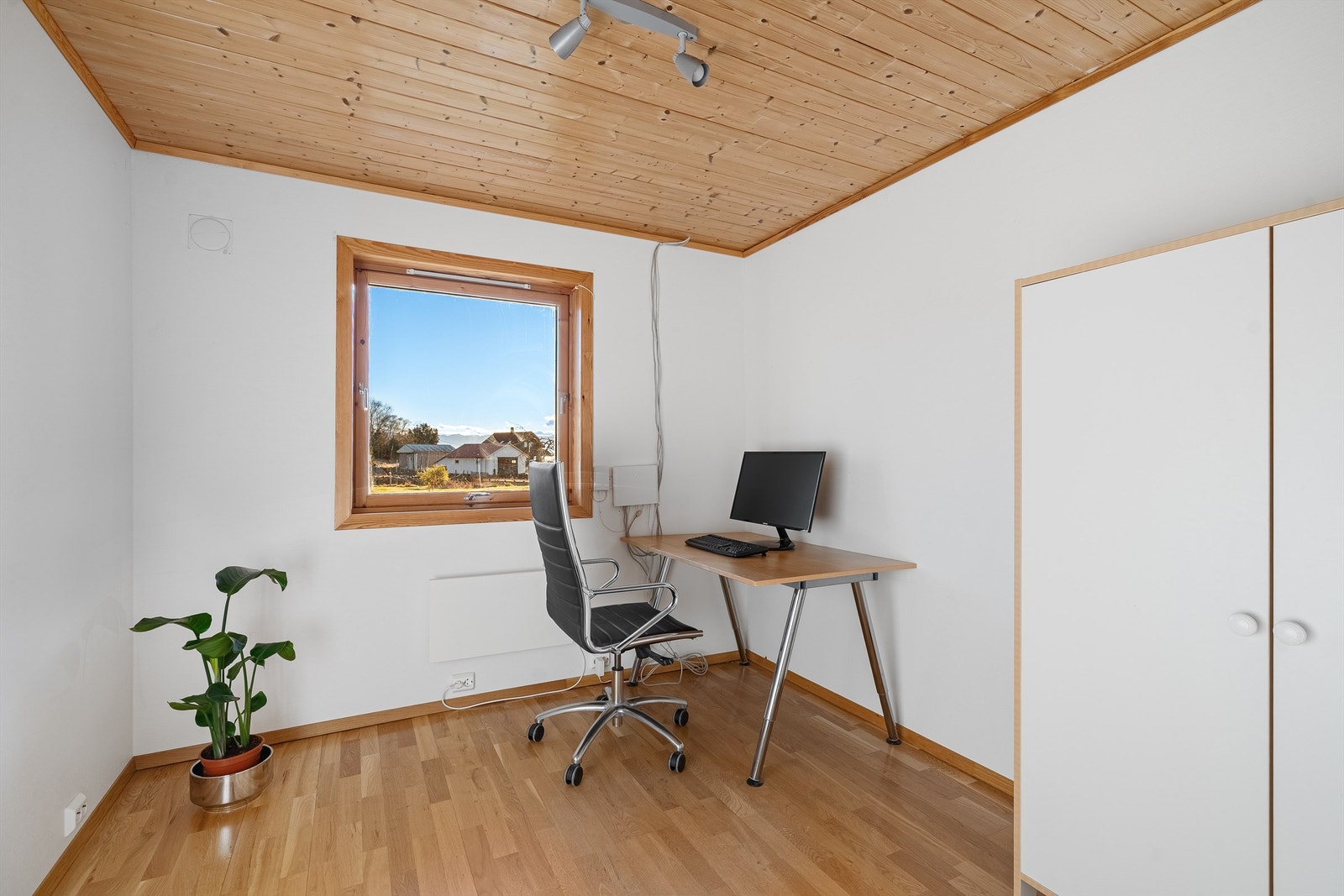 Et av soverommene i underetasjen, med parkett på gulvet og panel i taket. Galleribilde