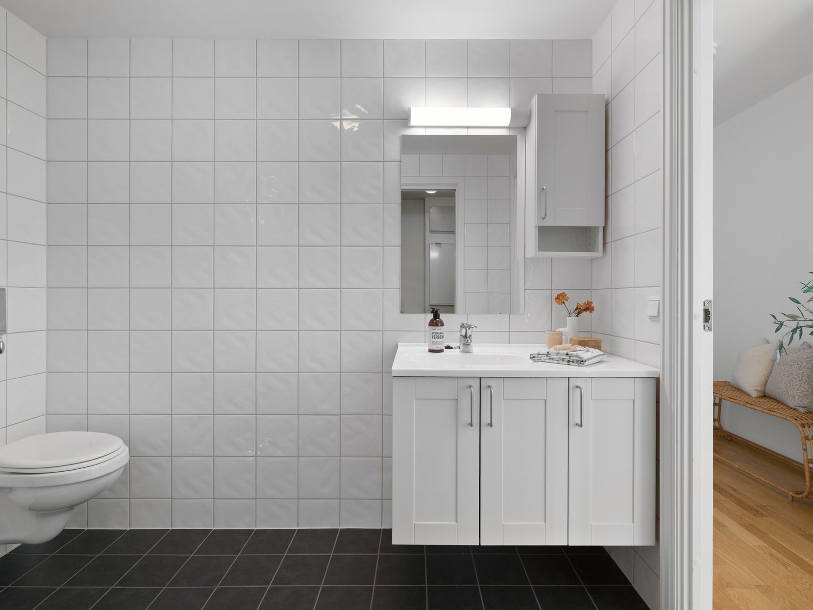 Rommet har fliser på gulv, samt fliser og strietapet på vegger. Badet/vaskerommet er innredet med servantskap og speil. Galleribilde