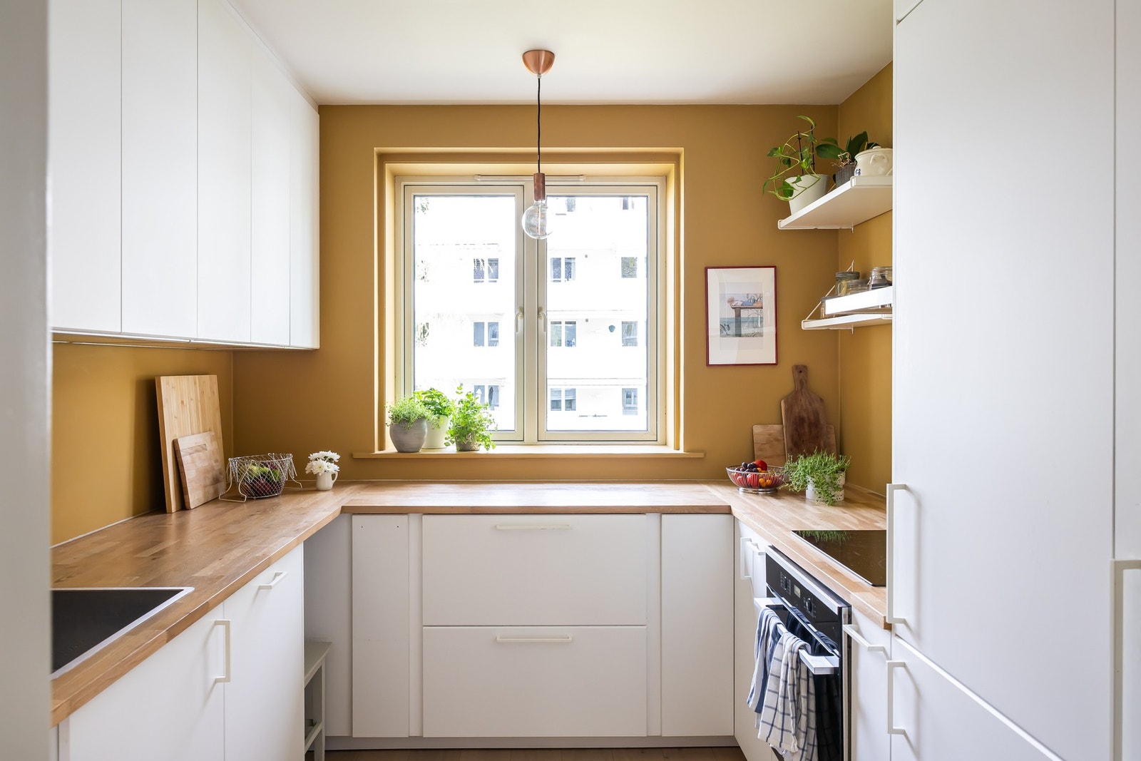 Separat kjøkken med innredning fra IKEA fra 2020, med hvite glatte fronter og benkeplate i eik. Galleribilde