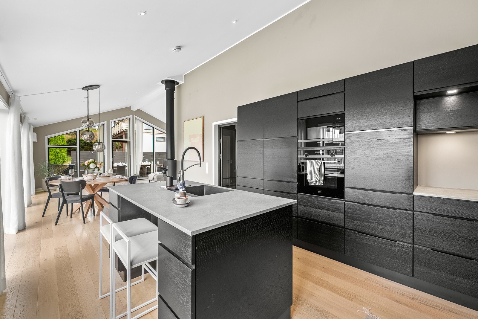 Åpen stue-/kjøkkenløsning med store vindusflater, downlights og enstavs parkett som gir et helhetlig og moderne uttrykk. Galleribilde