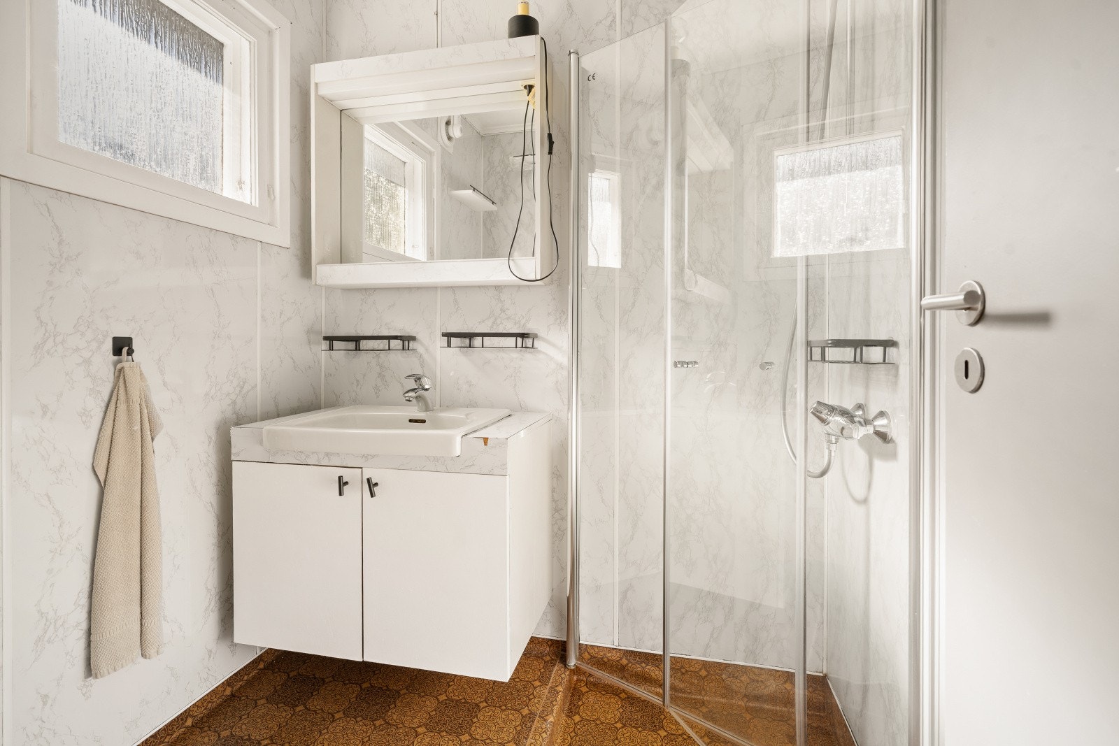 Badet i første etasje har våtromsplater på veggene og belegg på gulvet. Dusjhjørnet ble skiftet i 2022. Galleribilde