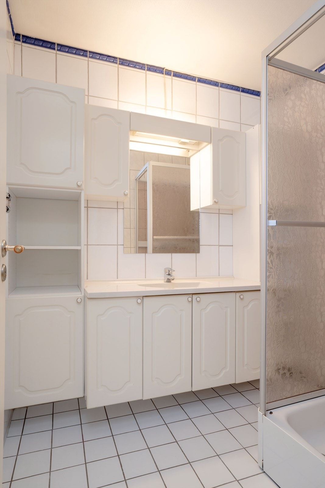 Badet er flislagt og har servant med innredning og dusjkabinett. Galleribilde