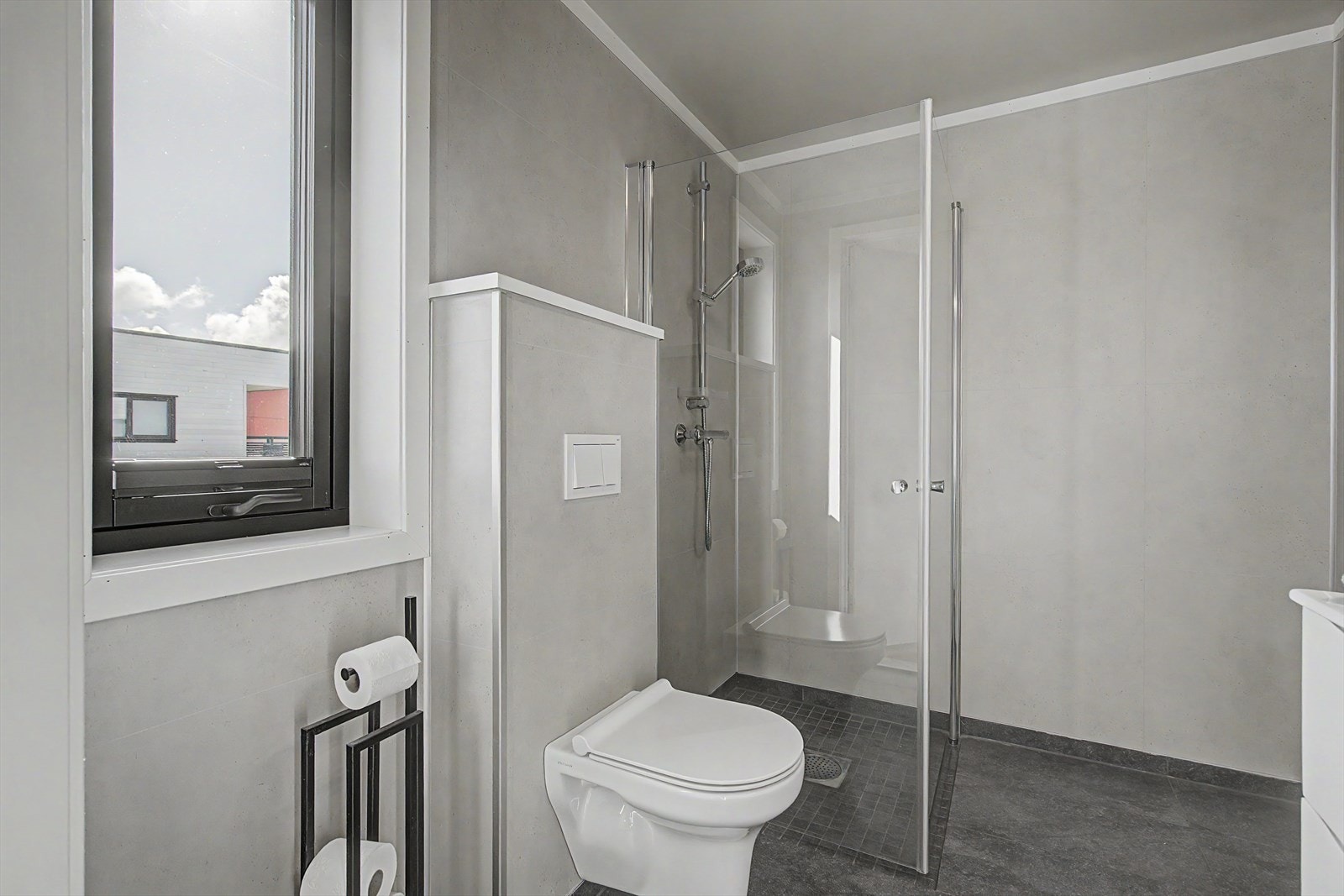 Badet har en nedsenket dusjsone med lokalt fall, vegghengt toalett og et vindu som gir naturlig lys. Galleribilde