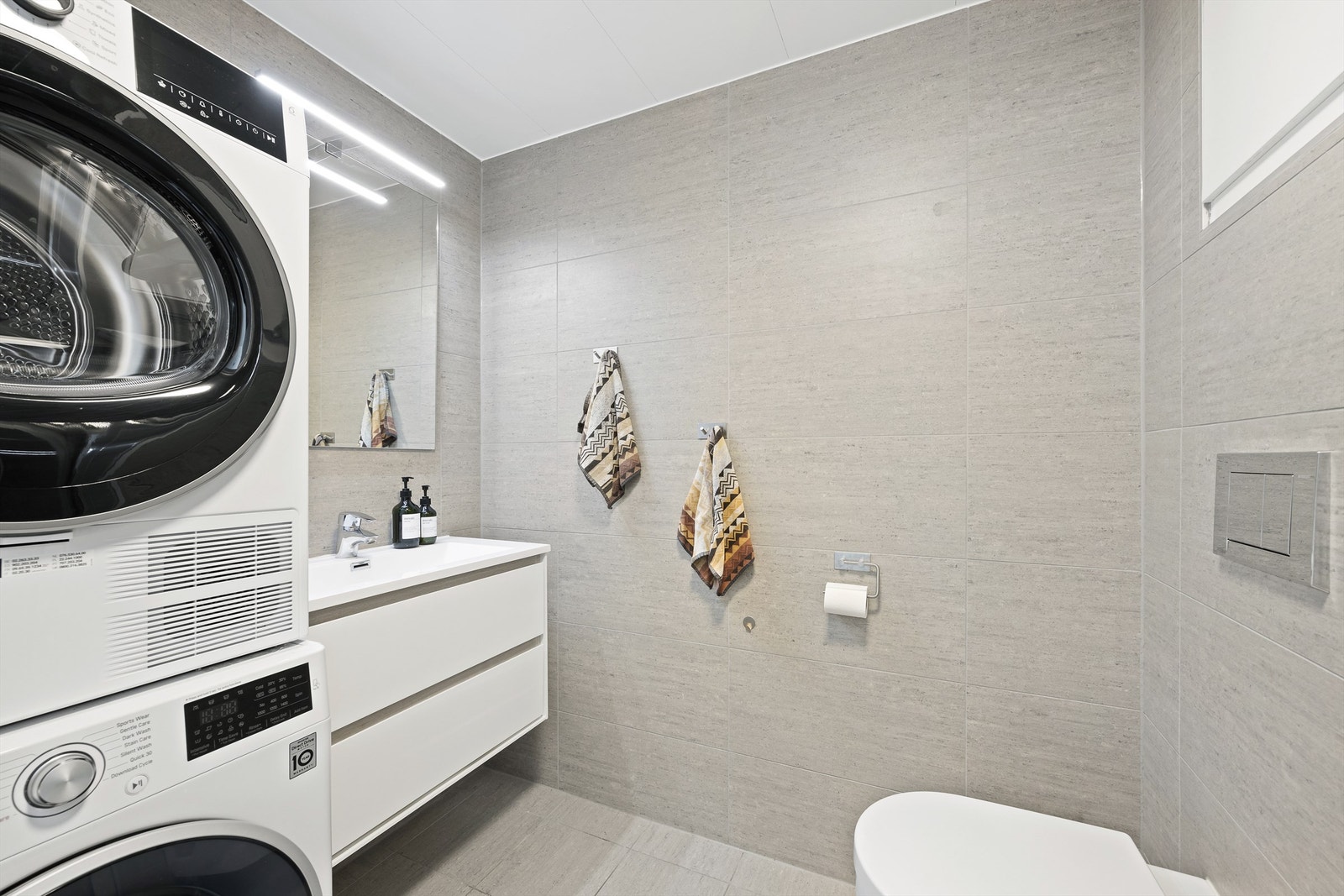 Lekkert og flislagt bad med gulvvarme. Plass og opplegg til vaskemaskin og tørketrommel. Badet er fra byggeår. Det ble i 2018 lagt flis på flis, samt ny servant, armatur og dusjarmatur Galleribilde