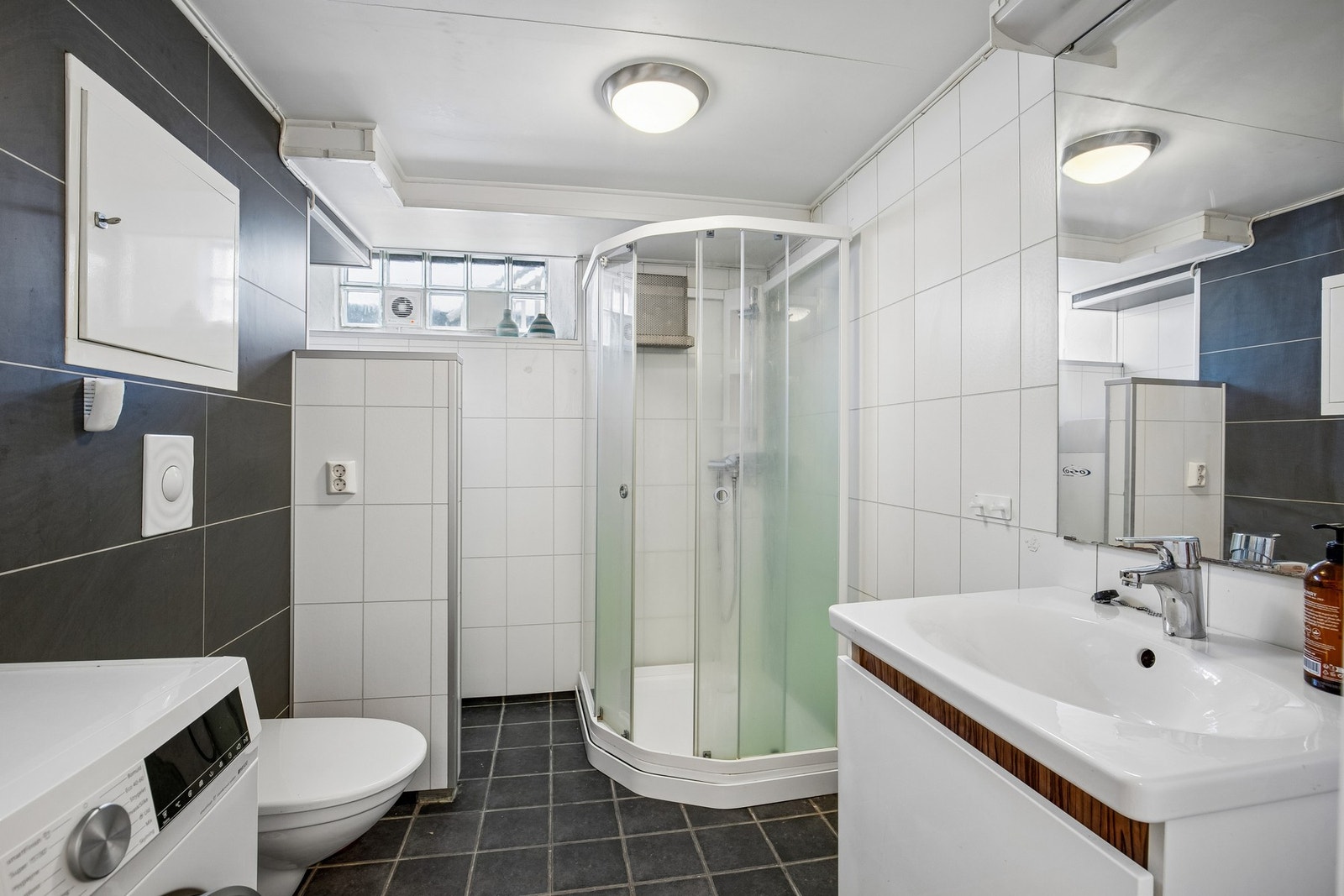 Bad fra ca. 2010 med flislagt gulv med elektriske varmekabler, våtromsplater på vegger og opplegg for vaskemaskin. Galleribilde
