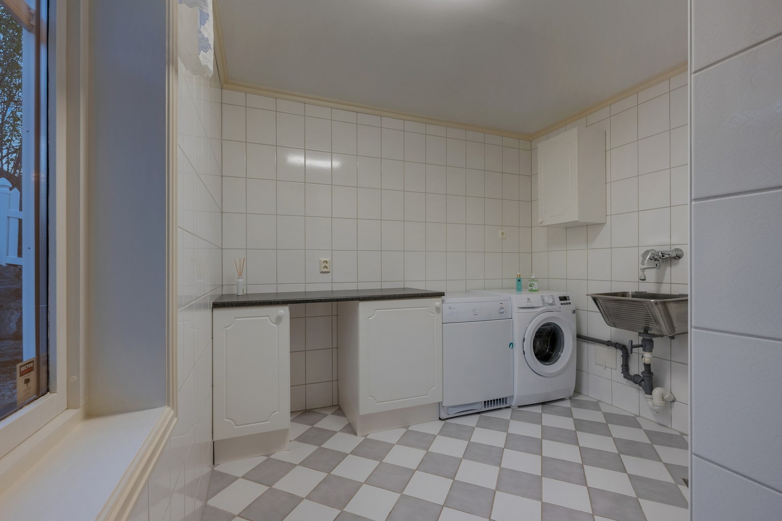 Vaskerommet er flislagt med gulvvarme og utstyrt med innredning, utslags kum og opplegg for vaskemaskin. Galleribilde