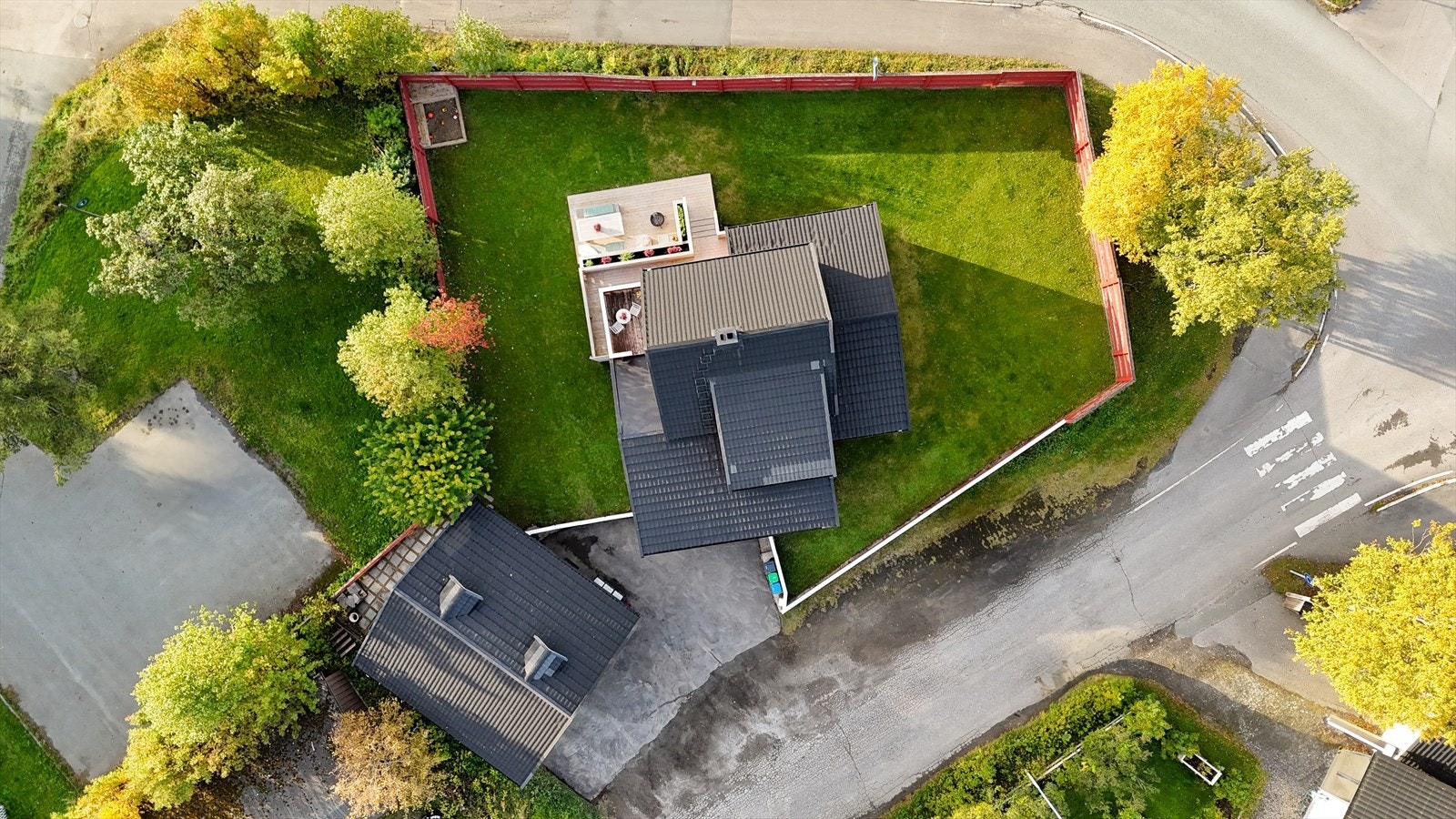 Eiendommen har en romslig og inngjerdet tomt med plen og asfaltert gårdsplass. Det bemerkes at selger har kjøpt ut tomten, slik at den nå er selveid. Galleribilde