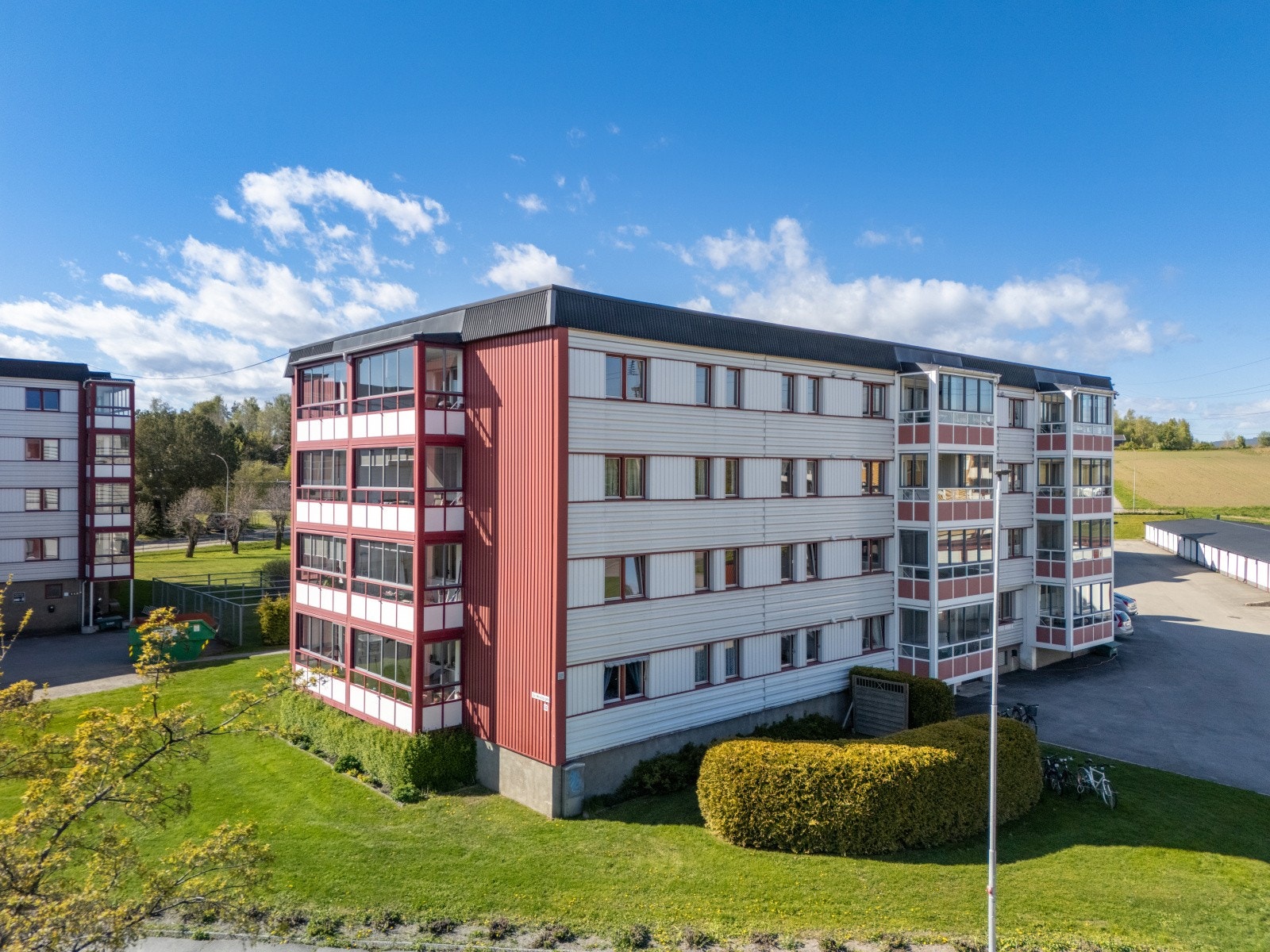 Et lavblokksbygg med flere leiligheter, omgitt av grønne områder og åpen himmel. Galleribilde