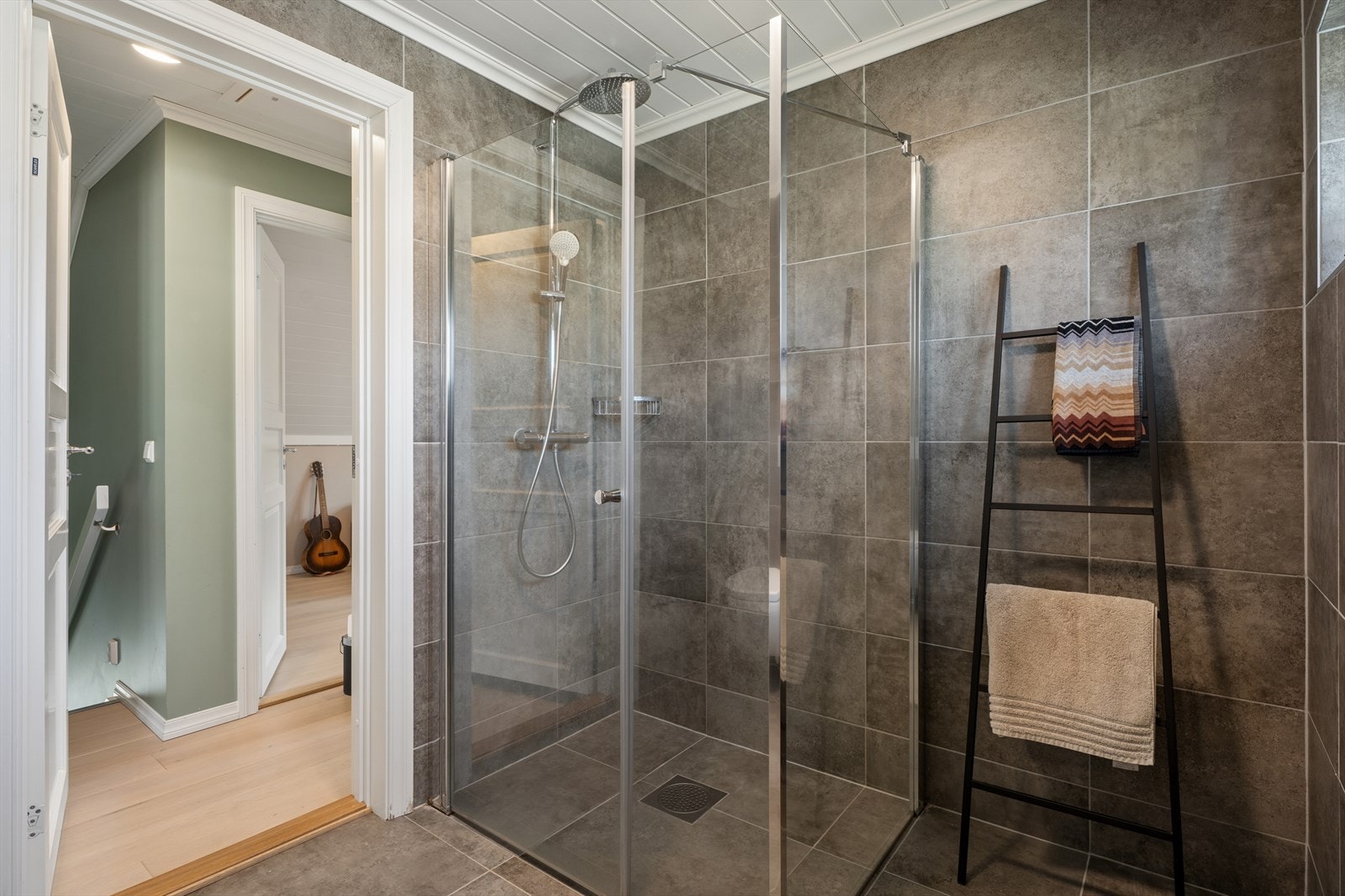 Badet i andre etasje har dusjhjørne med glassvegger og flislagte overflater. Galleribilde