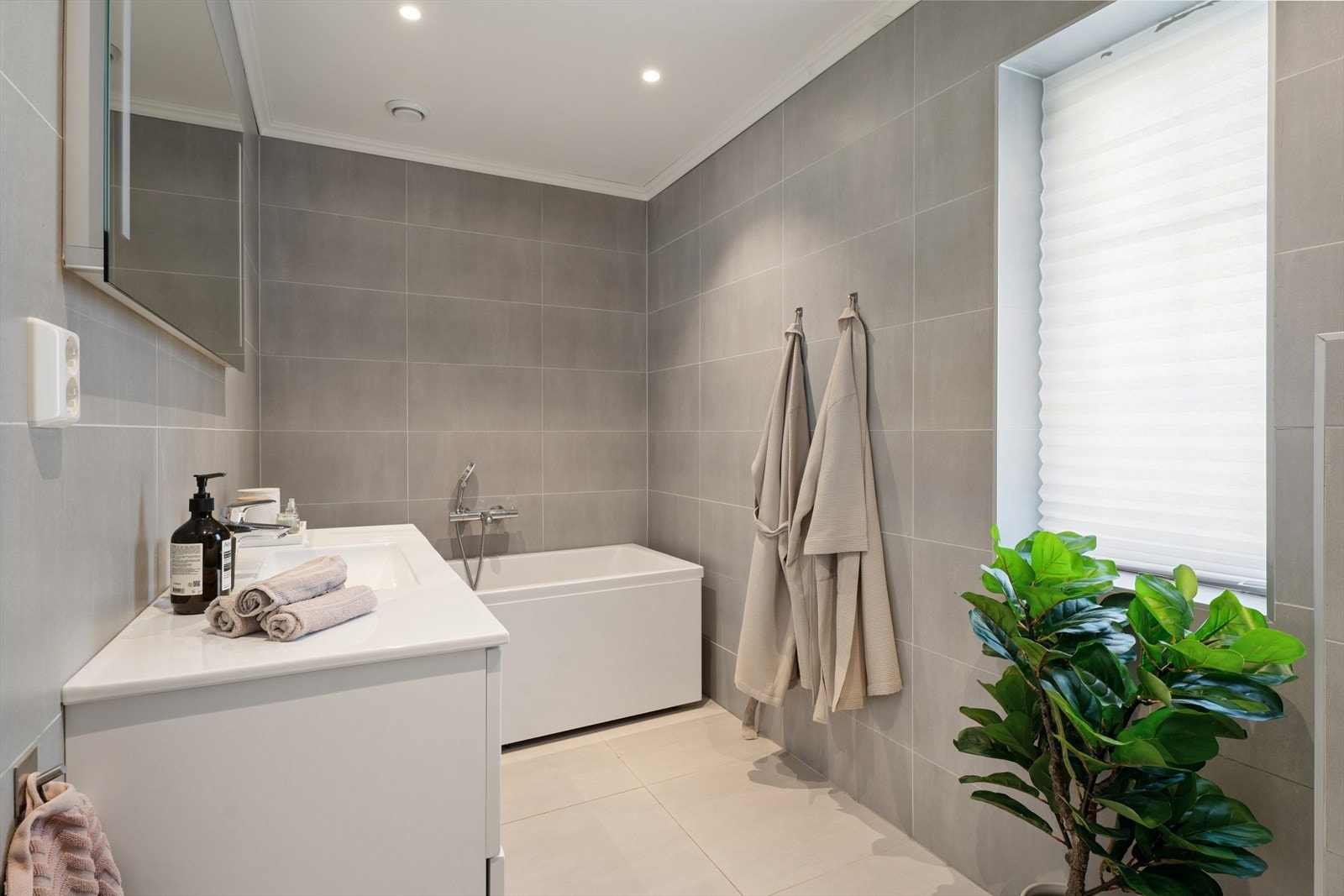 Badet i første etasje med flislagt gulv og vegger, utstyrt med badekar. Galleribilde