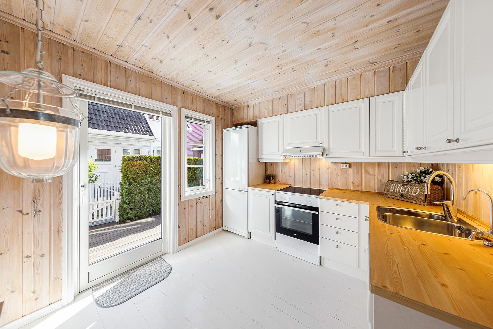 Tradisjonelt kjøkken med hvite profilerte fronter. Herfra er det utgang til sørvendt terrasse. Galleribilde