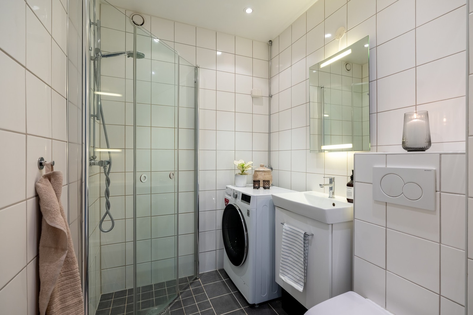 Boligens baderom er lyst, flislagt med varme i gulv og downlights i himling. Det er også opplegg for vaskemaskin. Galleribilde