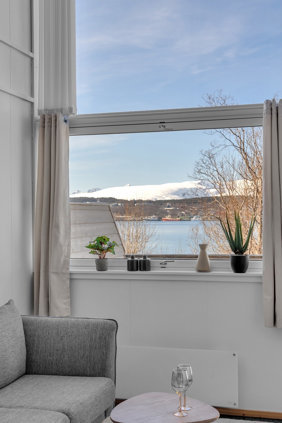 Fra stuevinduet kan du nyte nydelig utsikt over sundet, Tromsøya og de majestetiske fjellene på Kvaløya i bakgrunnen. Galleribilde