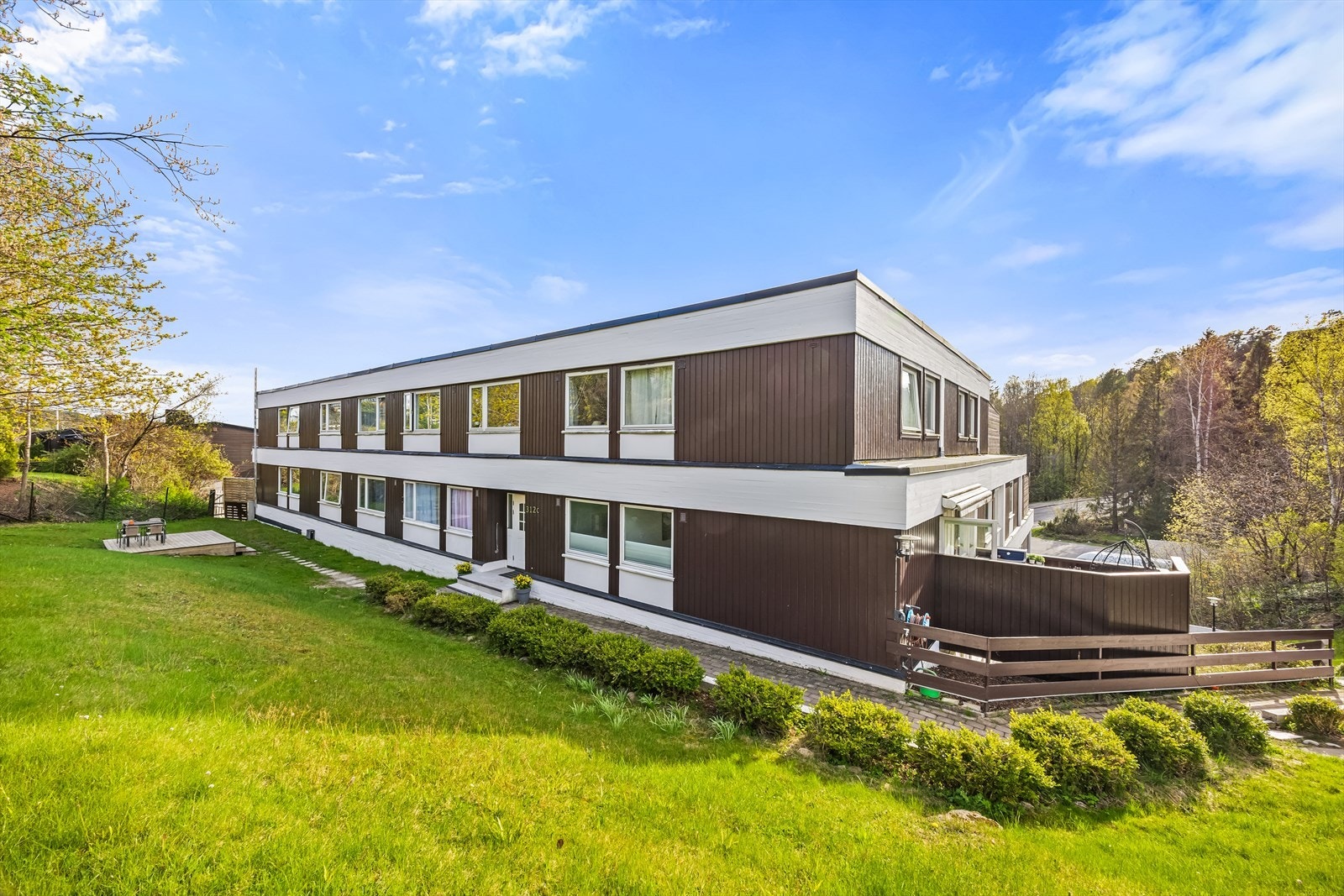 Pent opparbeidet fellesareal med asfalterte internveier, plen og beplantning. Galleribilde