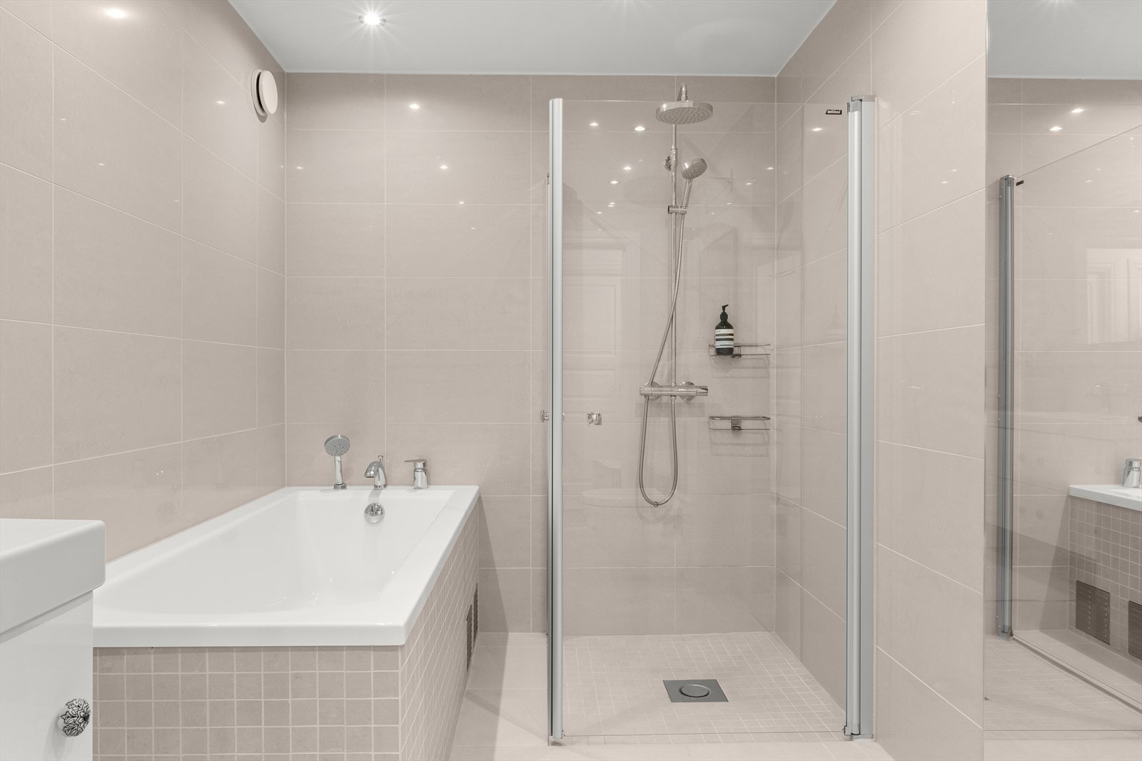 Badet er innredet med dusjhjørne, badekar, vegghengt toalett og opplegg for vaskemaskin og tørketrommel. Galleribilde