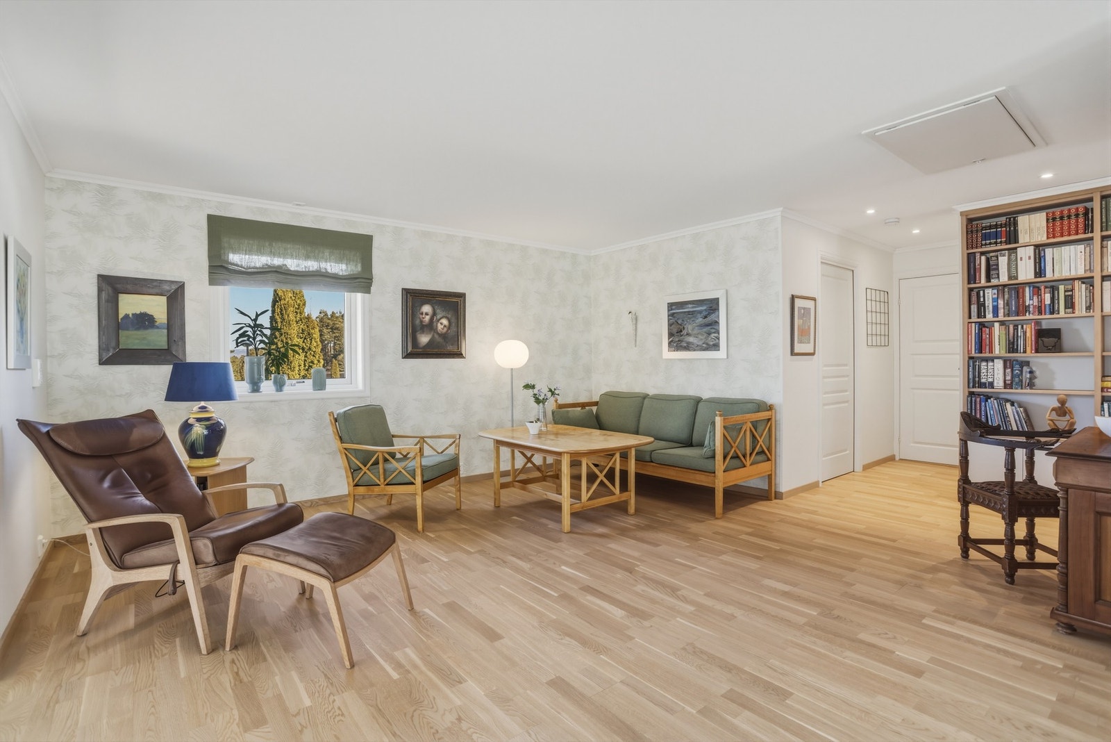 Lyst rom med parkettgulv, store vinduer og innebygd bokhylle. Galleribilde