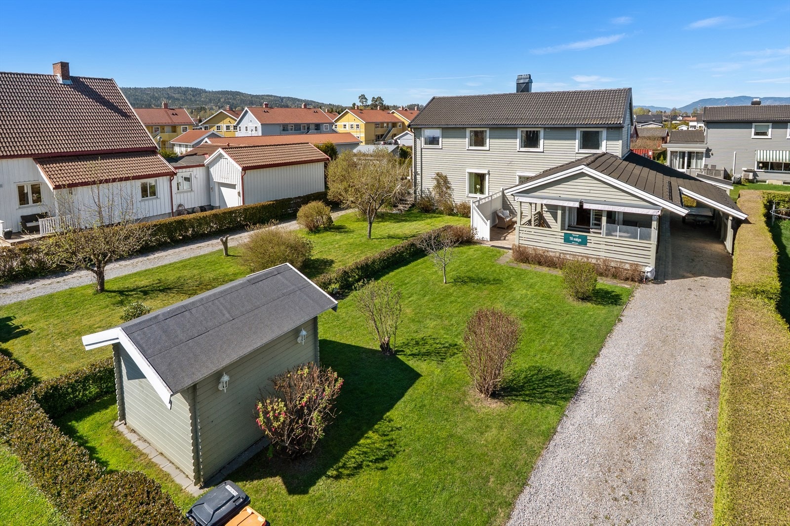 En innholdsrik bolig med solrik hage, carport og flere utvendige boder for praktisk lagring. Galleribilde