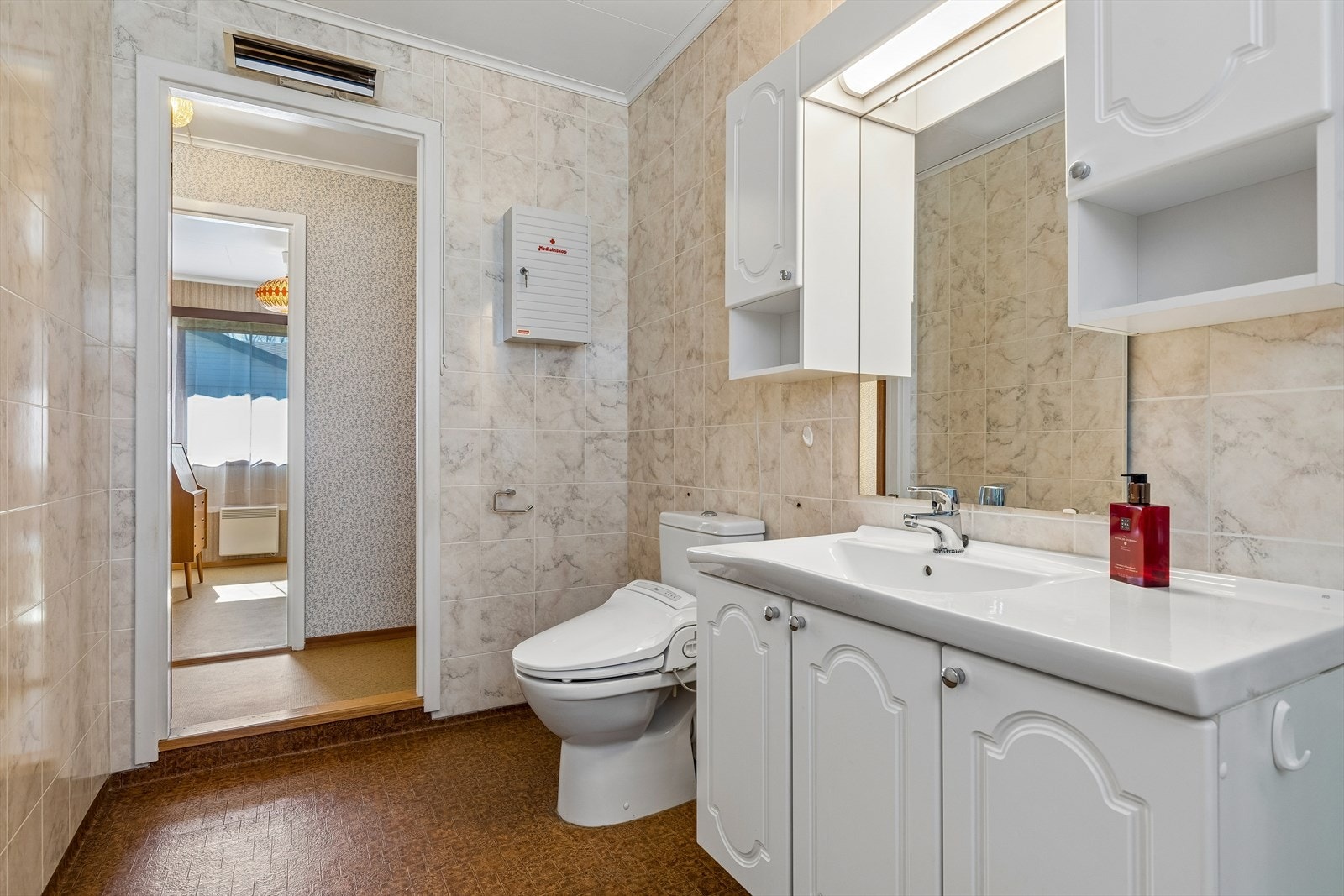 Eldre bad med med servantskap, speil og et toalett oppgradert med biobidet/dusjtoalettsete. Galleribilde