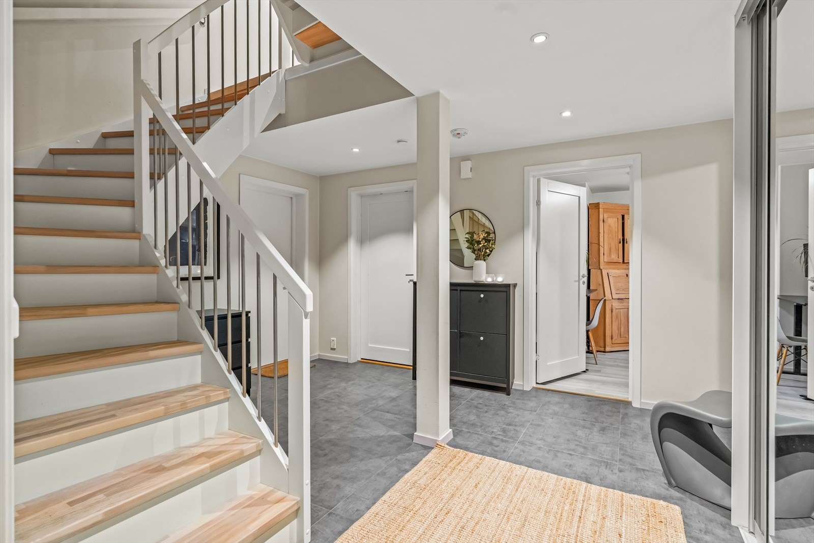 Entréen har gulvvarme, romslig speilgarderobe, store, grå gulvfliser, vegger med behagelig farge og downlights i himling. Det er dør direkte til garasjerommet og til teknisk rom/vaskerom. Galleribilde