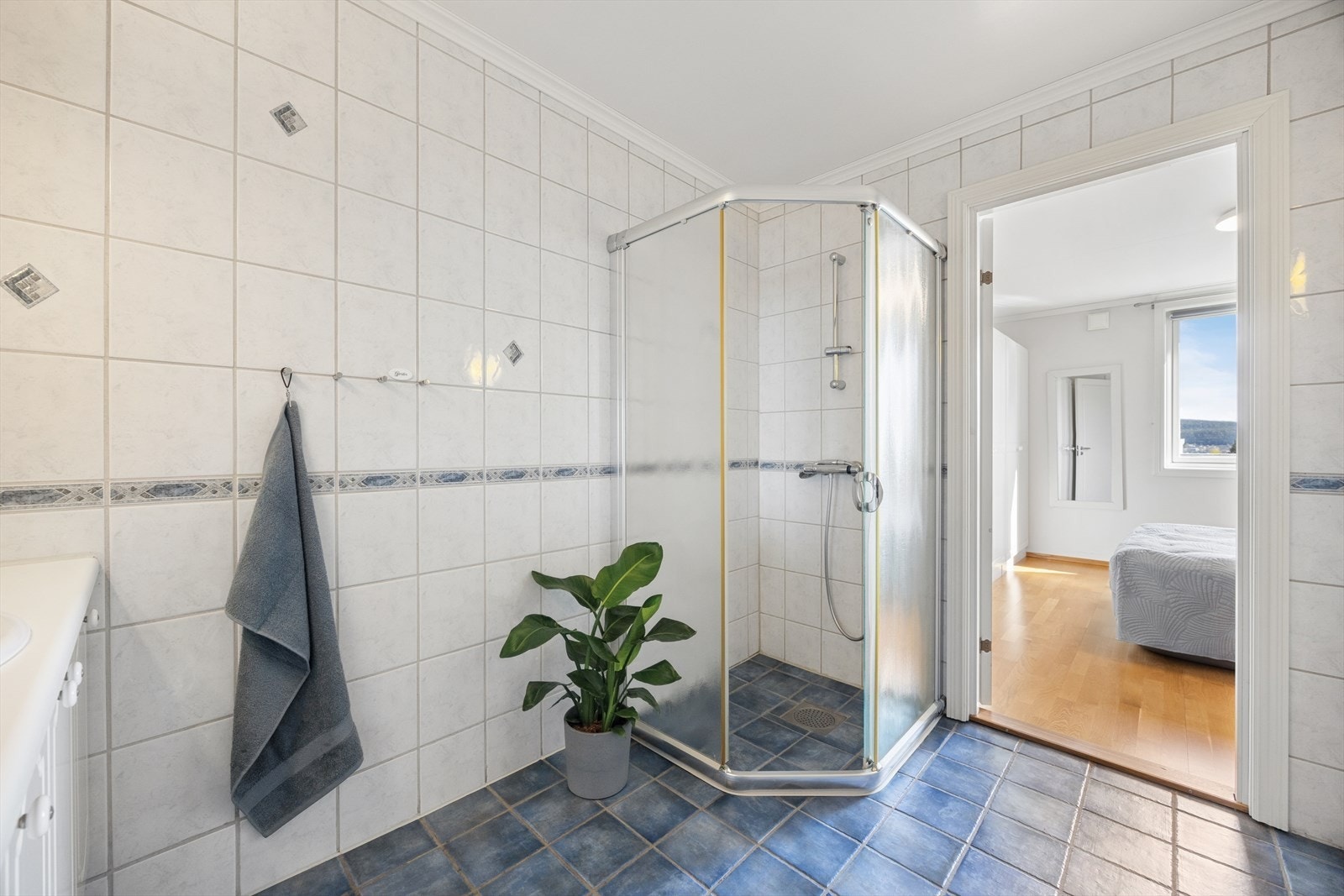 Badet har dusjhjørne med glassvegger, servant med underskap og gulvstående toalett. Galleribilde