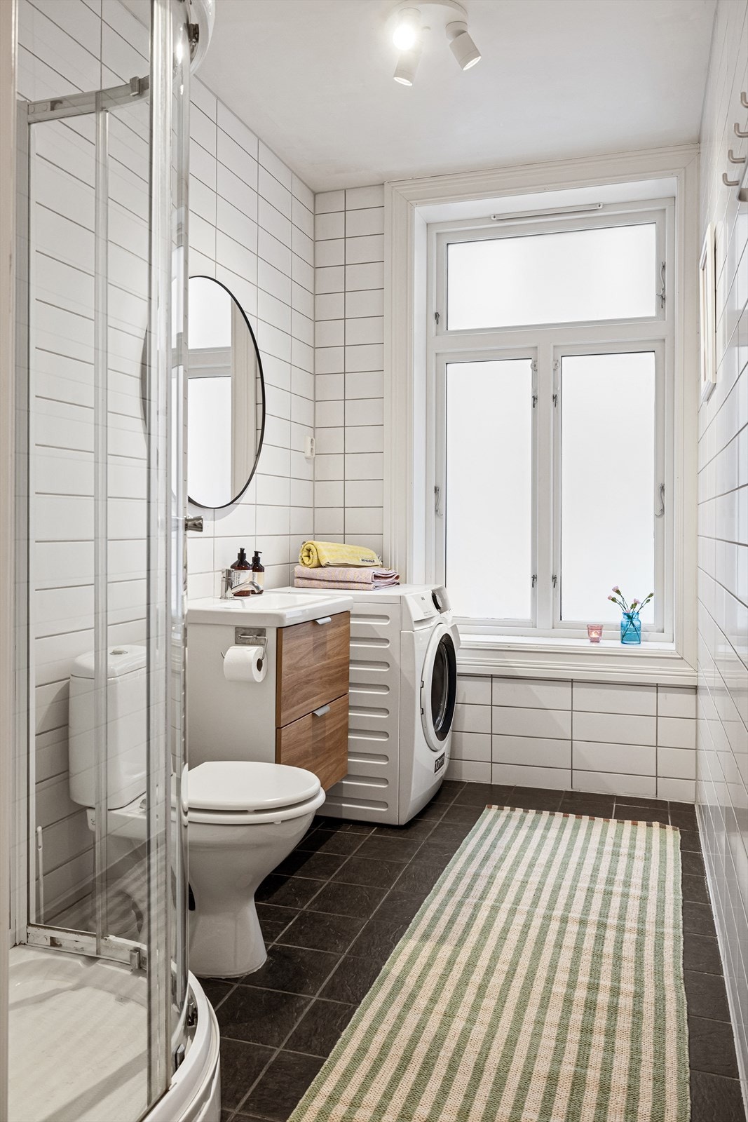 Romslig og pent, flislagt bad med vindu for rikelig med naturlig lys. På gulvet er det elektriske varmekabler og badet har opplegg for vaskemaskin/tørketrommel. Galleribilde