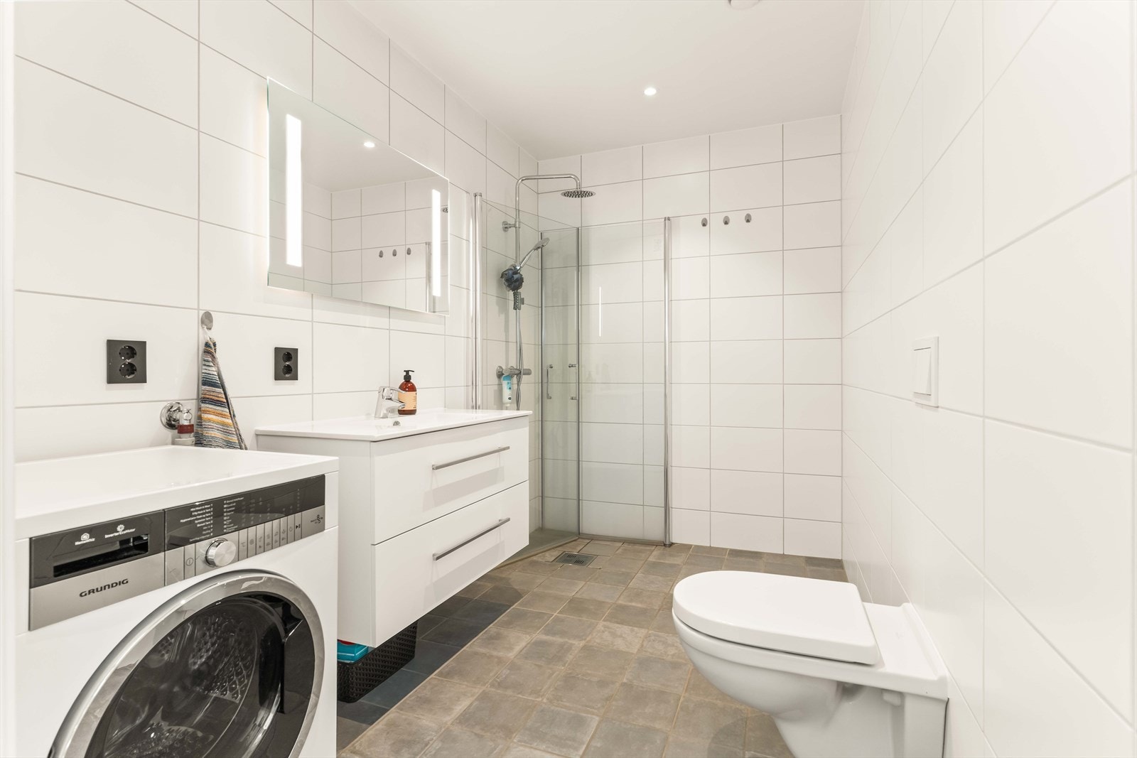 Badet er pent flislagt og er praktisk innredet med dusj og opplegg for vaskemaskin. Galleribilde