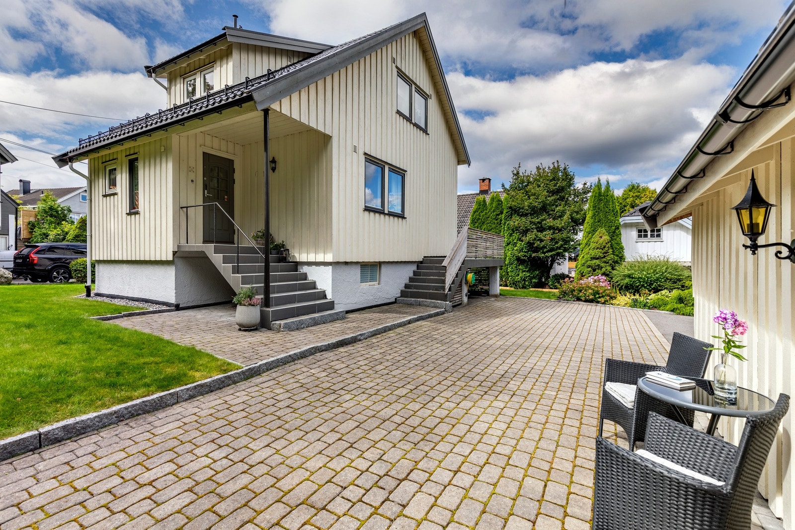 Stenlagt uteplass ved garasje og inngangspartiet til boligen. Galleribilde