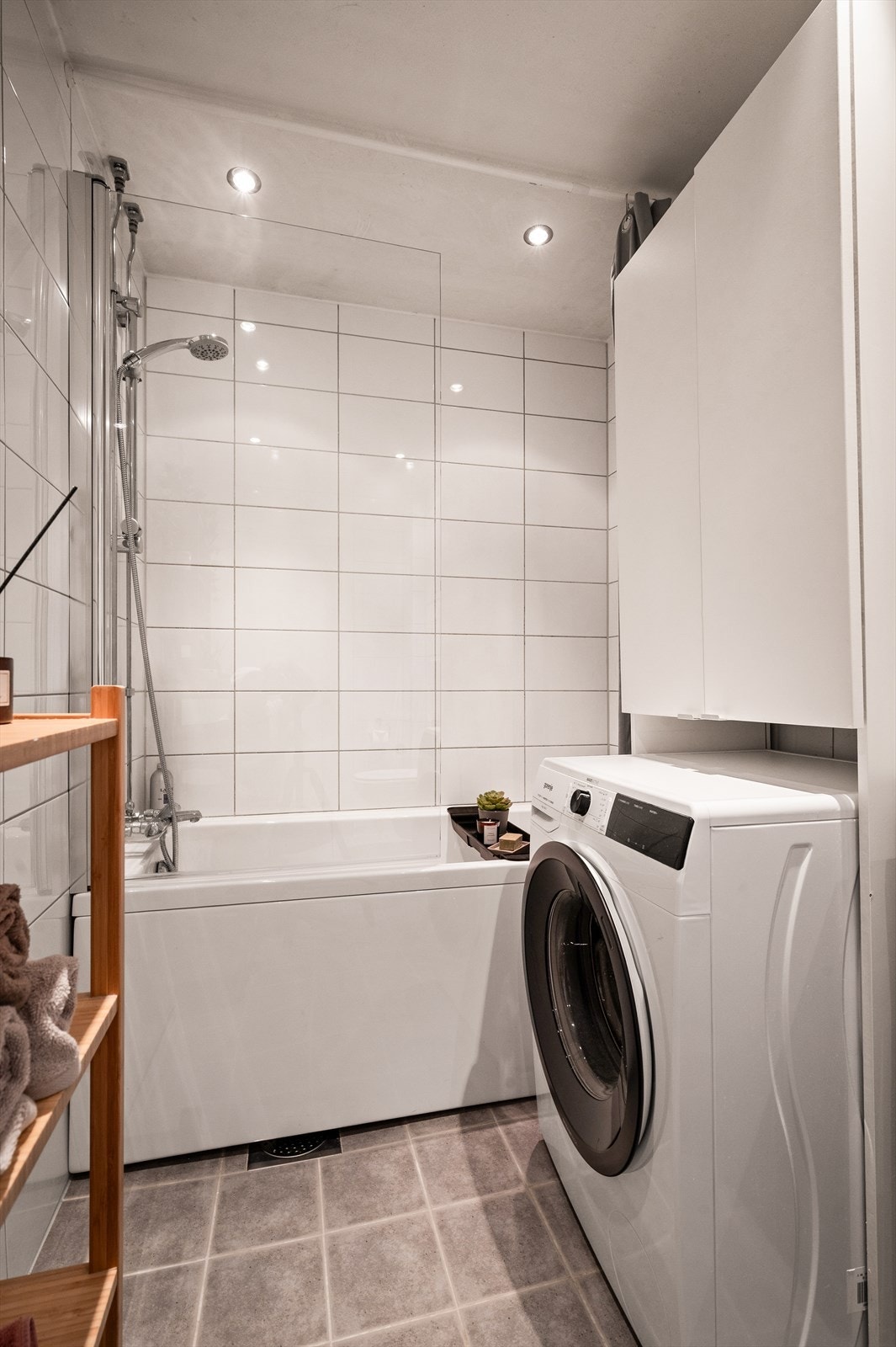 Badet har downlights i himling og er innredet med baderomsinnredning bestående av vegghengt klosett, servant med innredning, speilskap og badekar med dusj. Galleribilde