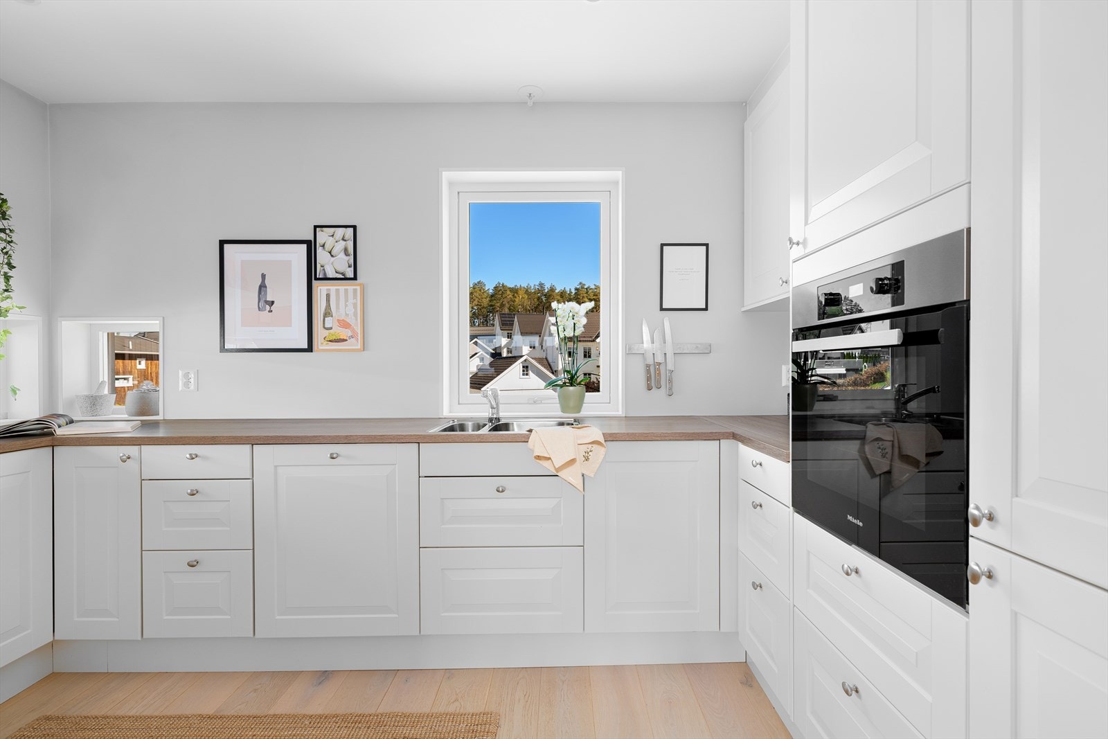 Det tidløse kjøkkenet er innredet med lyse, profilerte fronter og laminert benkeplate. Galleribilde