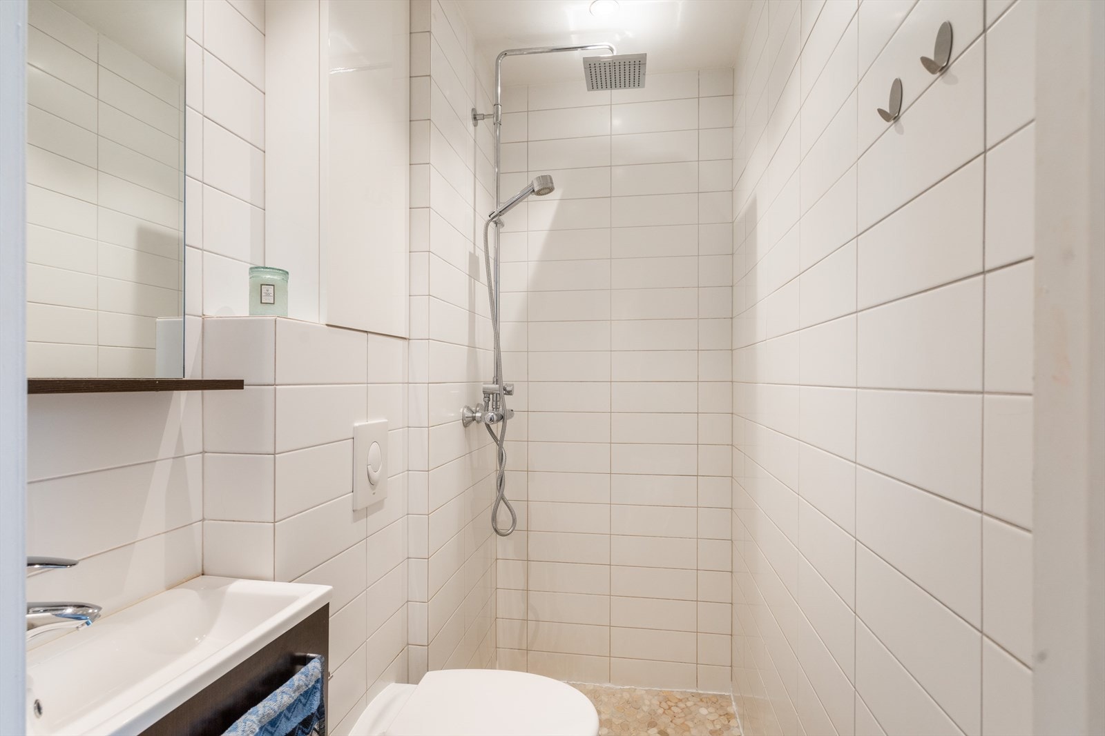 Badet har åpen dusjløsning, servantinnredning, speil og veggmontert toalett. Galleribilde