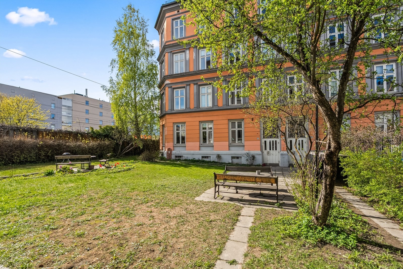 Inngjerdet felles forhage med trær, plen, beplantning og sittegrupper. Galleribilde