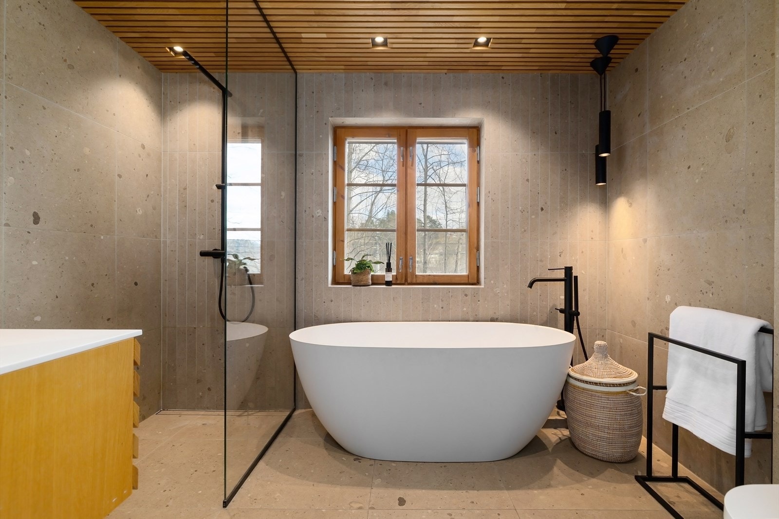 : Moderne baderom fra 2023 som er smakfullt innredet med tidløse fliser på gulv og vegger, samt spiler i himling med downlights for behagelig belysning. Galleribilde