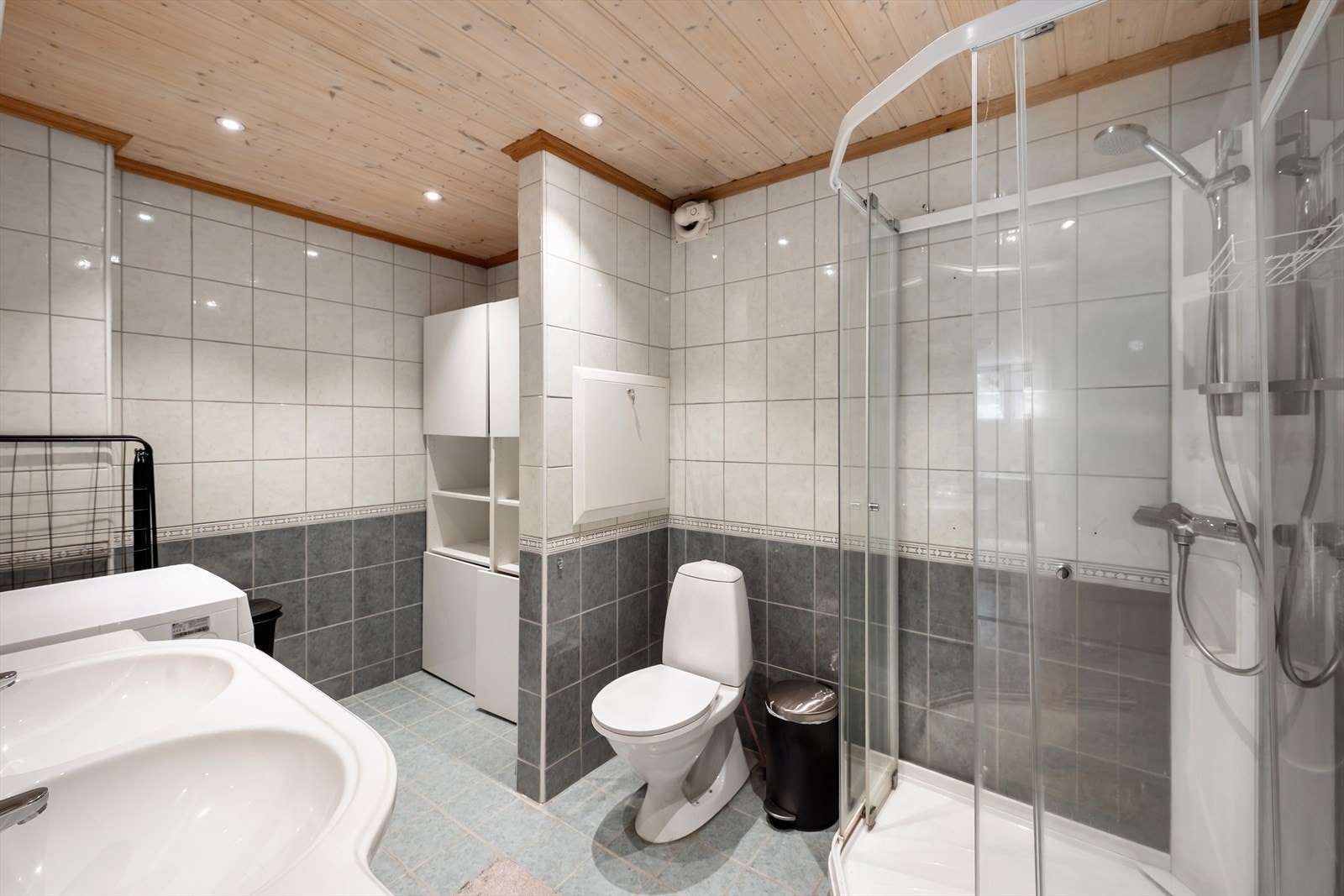 Badet i underetasjen har flislagt gulv med varmekabler, dusjkabinett og opplegg for vaskemaskin. Galleribilde