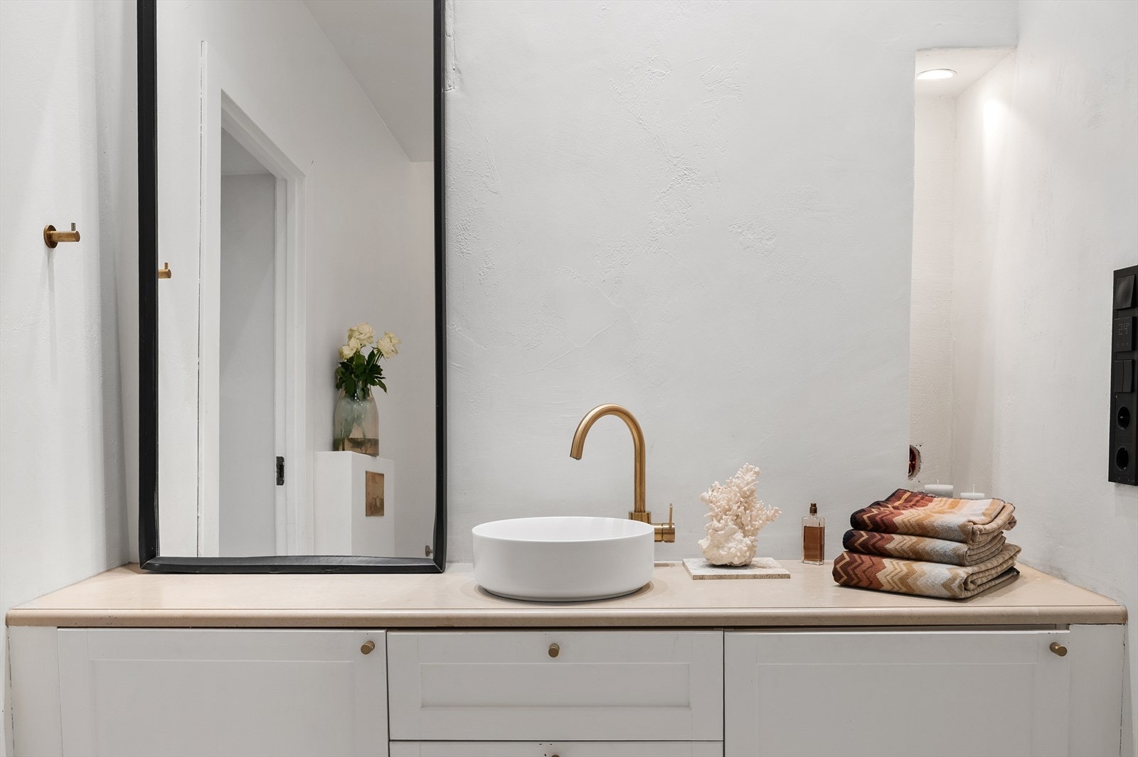 Badet er utstyrt med servant og innredning med skap og skufffer. De varme metalltoner tilfører karakter og eleganse Galleribilde