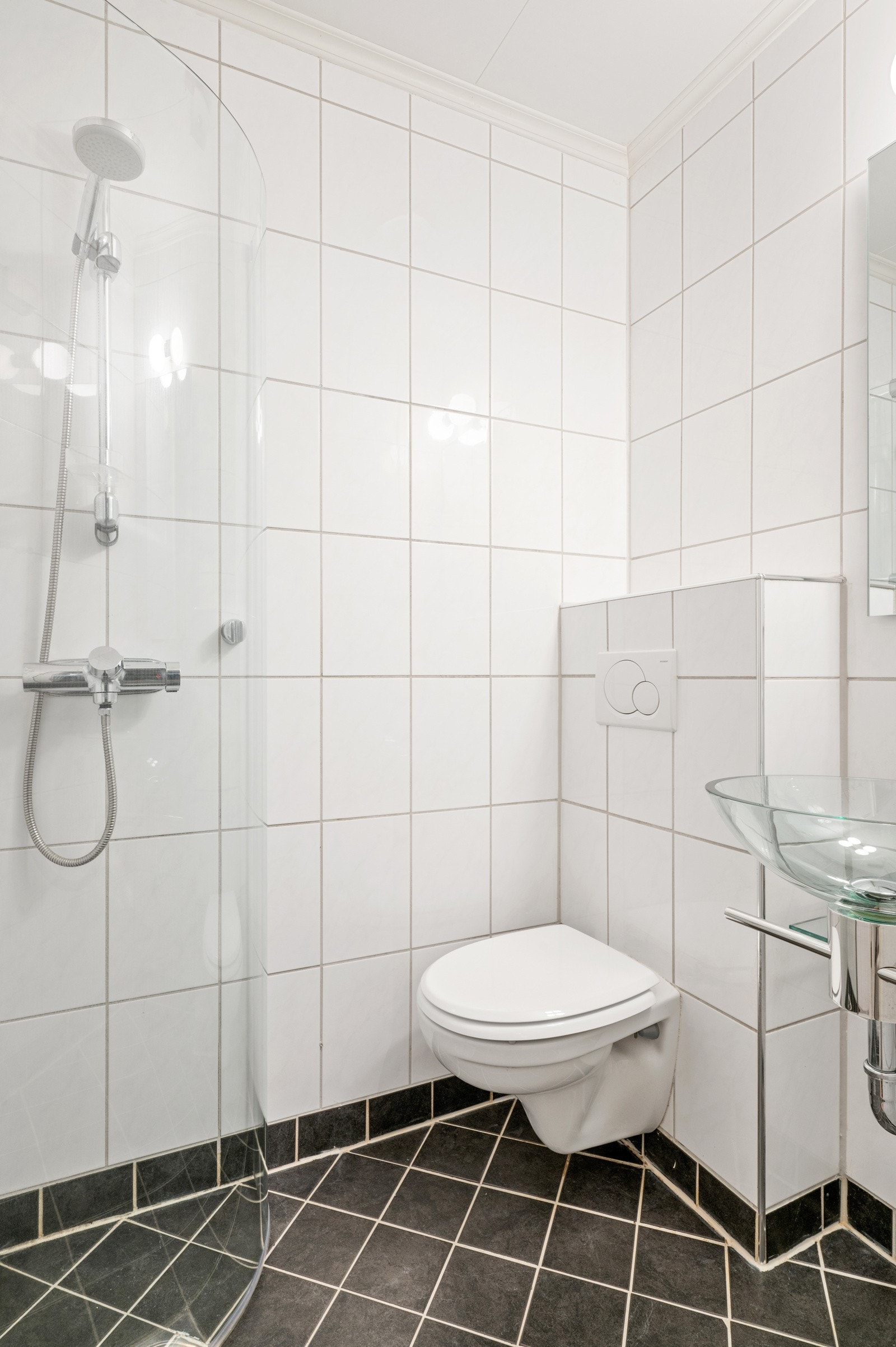 Flislagt bad fra 2005 med varmekabler i gulv, dusjløsning, vegghengt toalett og servant. Galleribilde