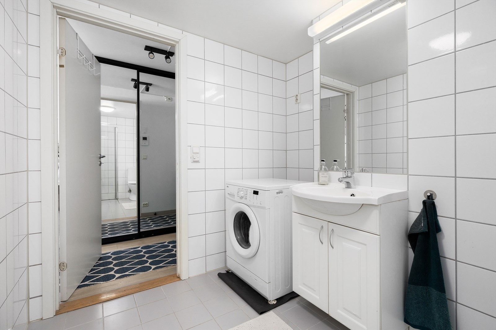 Badet er utstyrt med et gulvmontert toalett, en vegghengt servantinnredning, et dusjhjørne med foldbare glassdører samt opplegg for vaskemaskin. Galleribilde