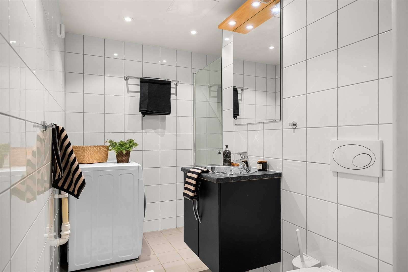 Pent og flislagt bad på 4,5m² med sort fargevalg på innredning. Det er behagelig gulvvarme som varmekilde på badet. Galleribilde