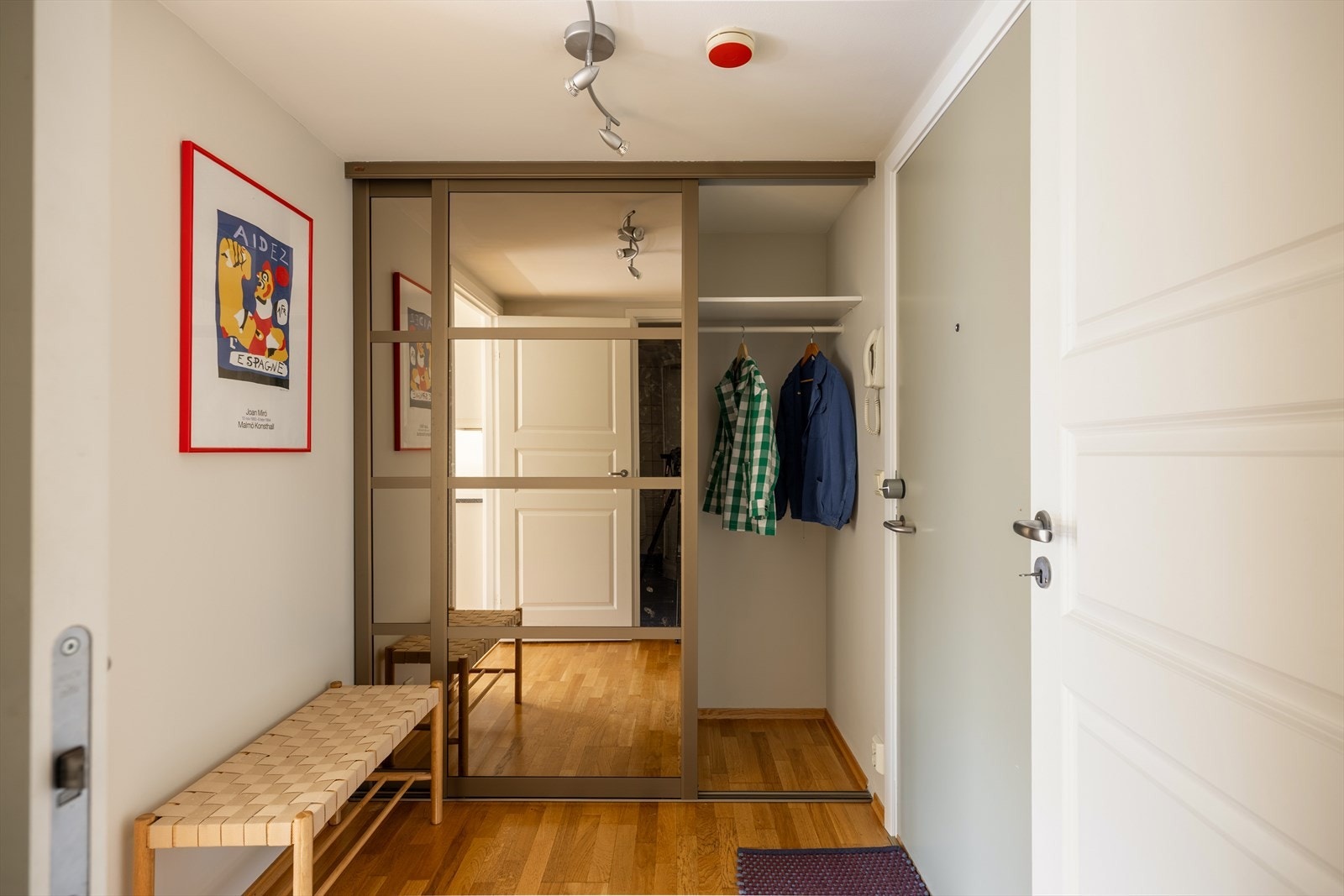 Romslig og innbydende entré med praktisk innebygd skyvedørsgarderobe og inngang til en liten nisje/bod Galleribilde