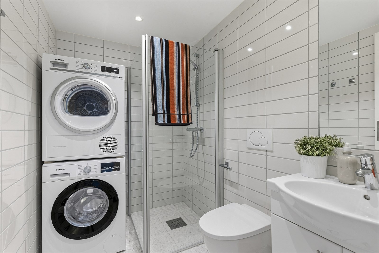 Bad/ vaskerom som er helfliset. Det er downlights i tak og det er vannbåren gulvvarme. Innredet med nedfelt servant, veggmontert toalett, dusjvegger i hjørne og opplegg for vaskemaskin. Balansert ventilasjon. Galleribilde