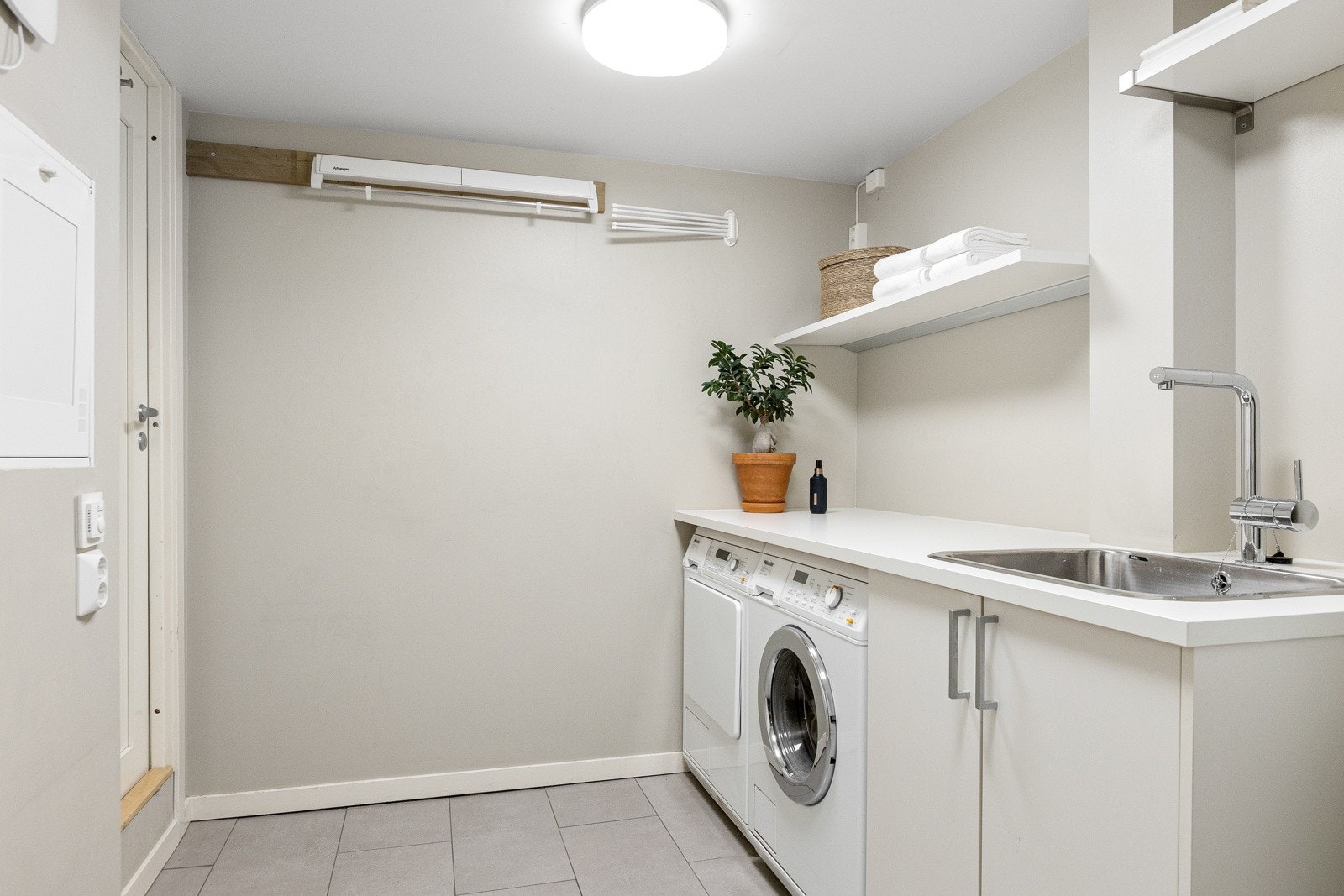 Vaskerommet har flislagt gulv og vegger med malte plater. Rommet er tilrettelagt med opplegg for vaskemaskin og tørketrommel, samt innredning med nedfelt vask. Det er elektriske varmekabler i gulvet. Galleribilde