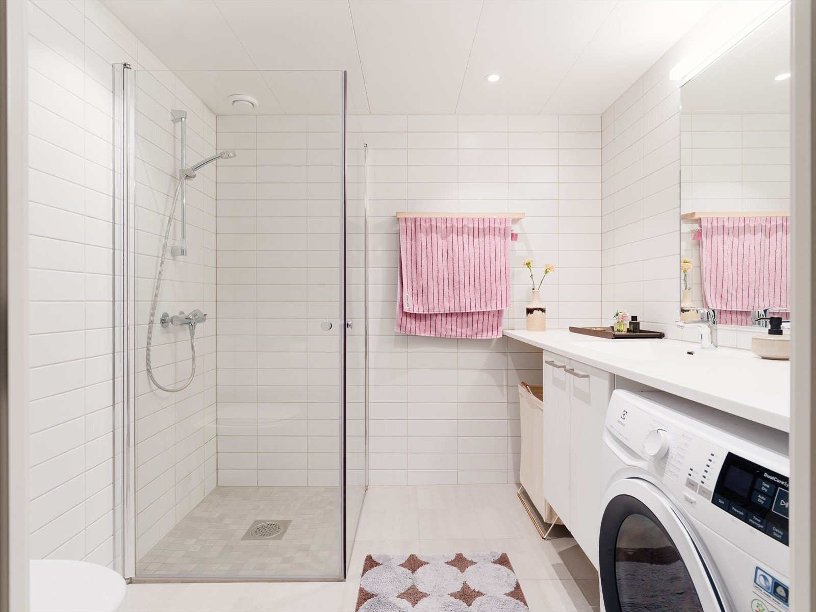 Delikat flislagt baderom med varme i gulv og downlights i himling. Badet er også innredet med praktisk dusjhjørne med innfellbare dusjdører, klosett, servant med innredning, og opplegg for vaskemaskin. Galleribilde
